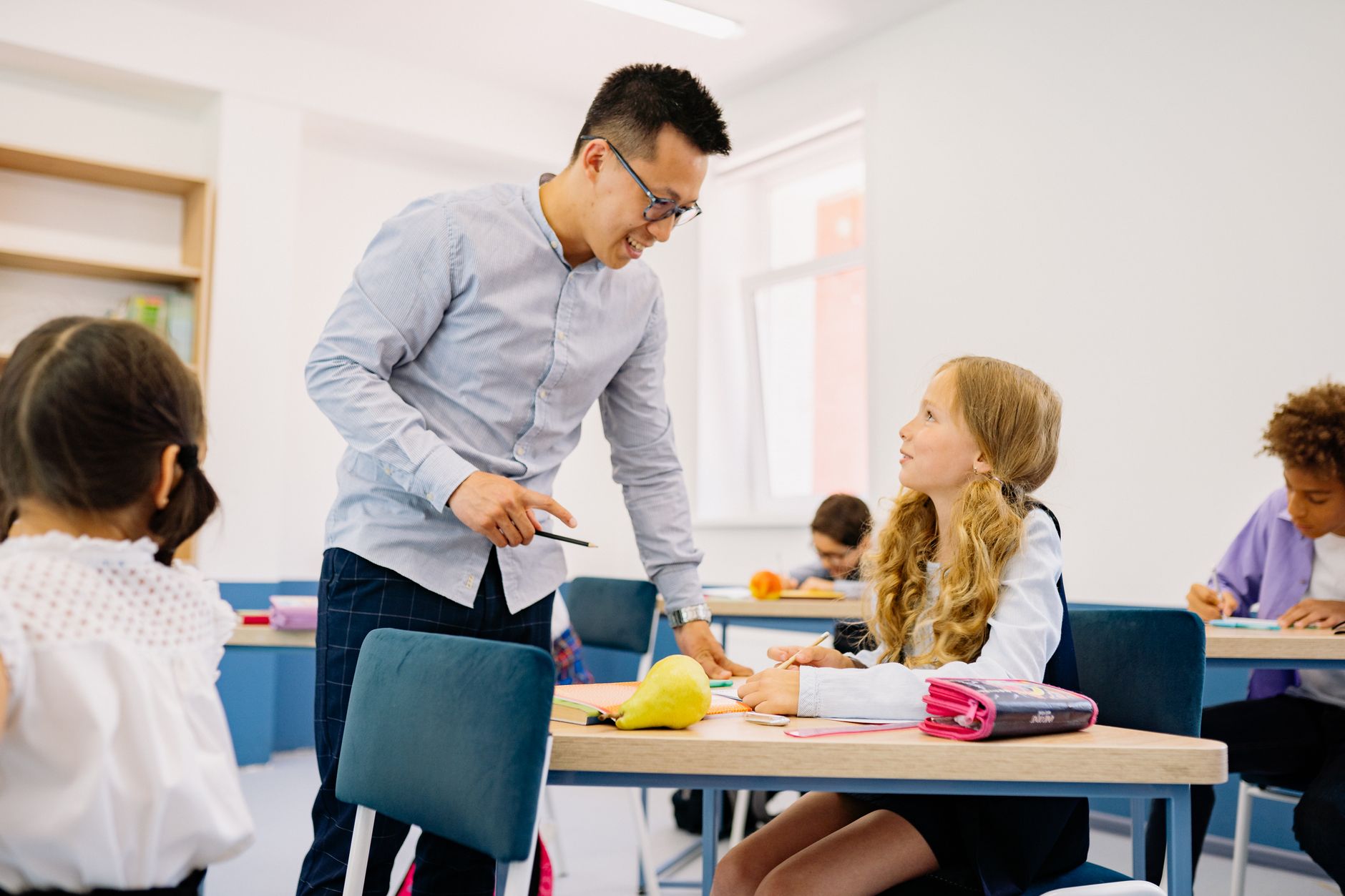 Professional Development and Reflective Practice — A male teacher interacting with diverse students in a bright classroom setting, promoting active learning.