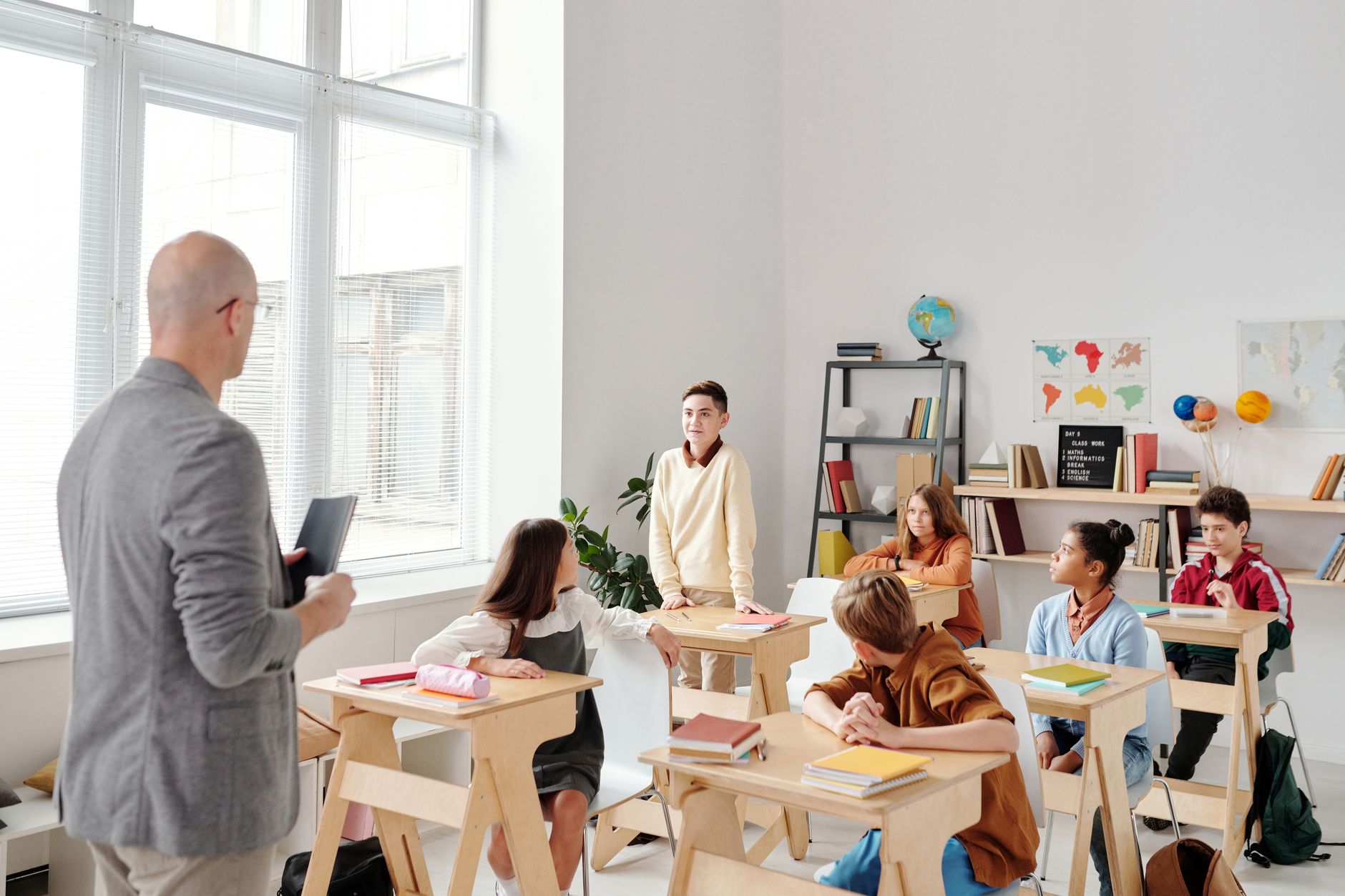 Contemporary Issues in Education: Theory, Policy and Practice — A diverse group of students engaged in learning with a male teacher in a modern classroom setting.