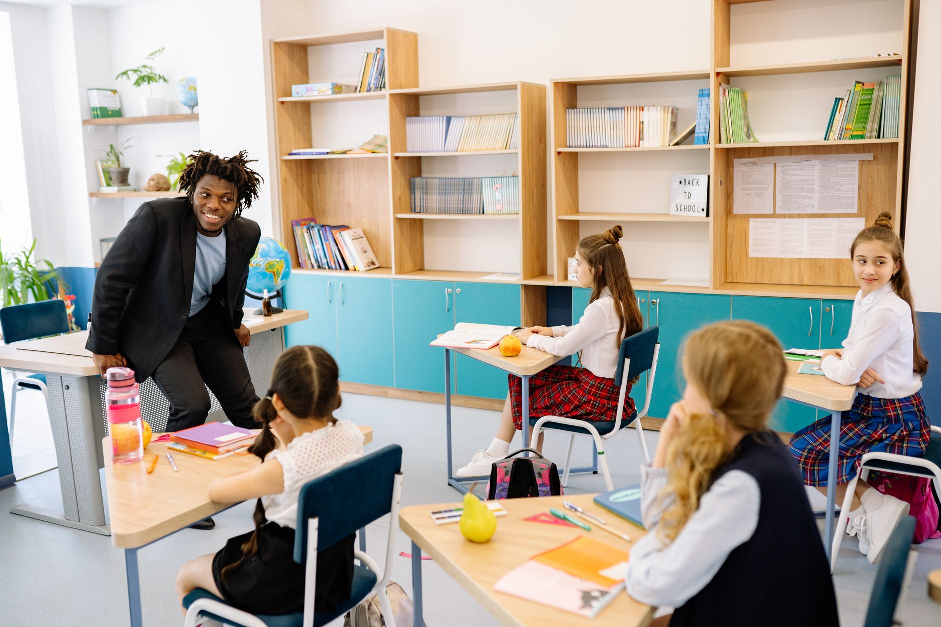 The Effective use of Resources for TEFL — Teacher engaging students in a bright classroom, fostering interactive learning.