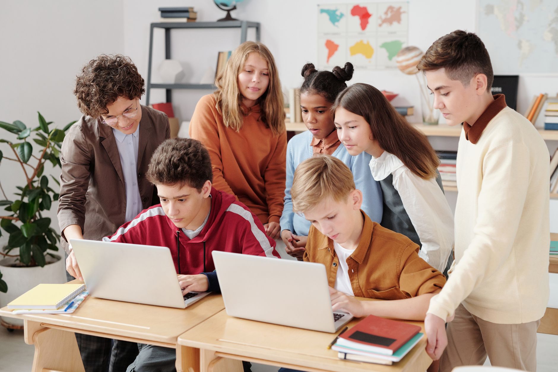 Awareness of Learners — A group of diverse students collaborating on laptops in a classroom setting, guided by a teacher.