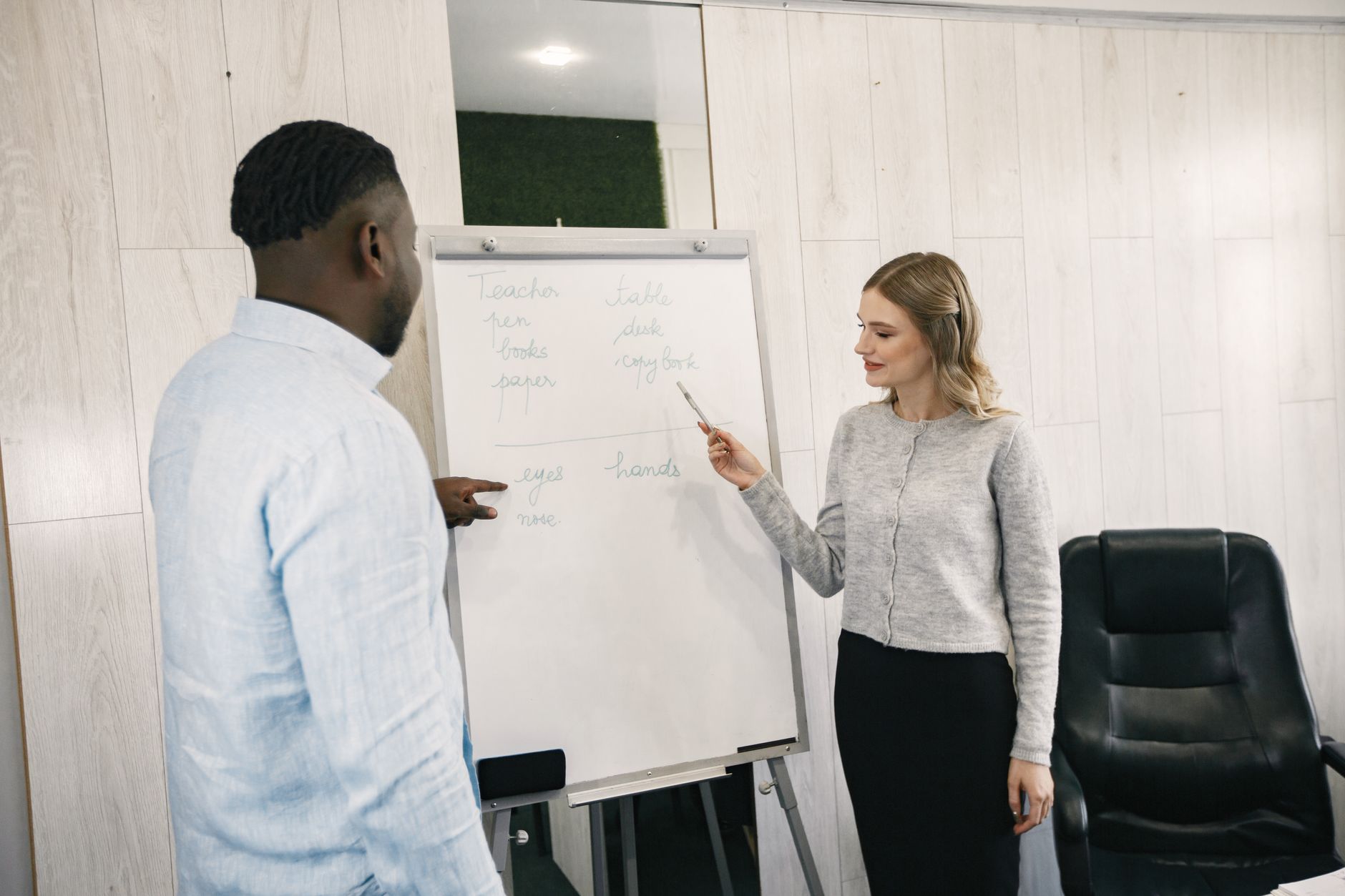 The Foundations of Coaching — A diverse team having a discussion in front of a flip chart inside an office.
