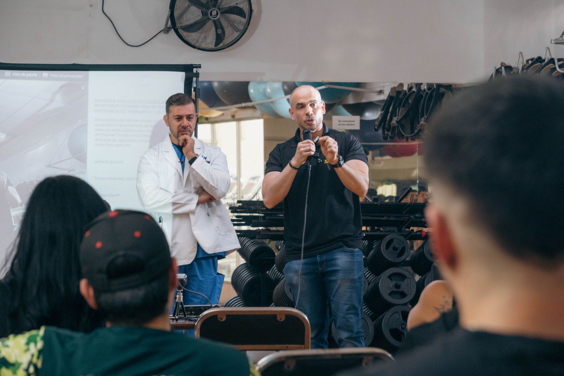 Building a business as a Health/Wellness Coach — A doctor and fitness trainer conducting a seminar in a gym setting.
