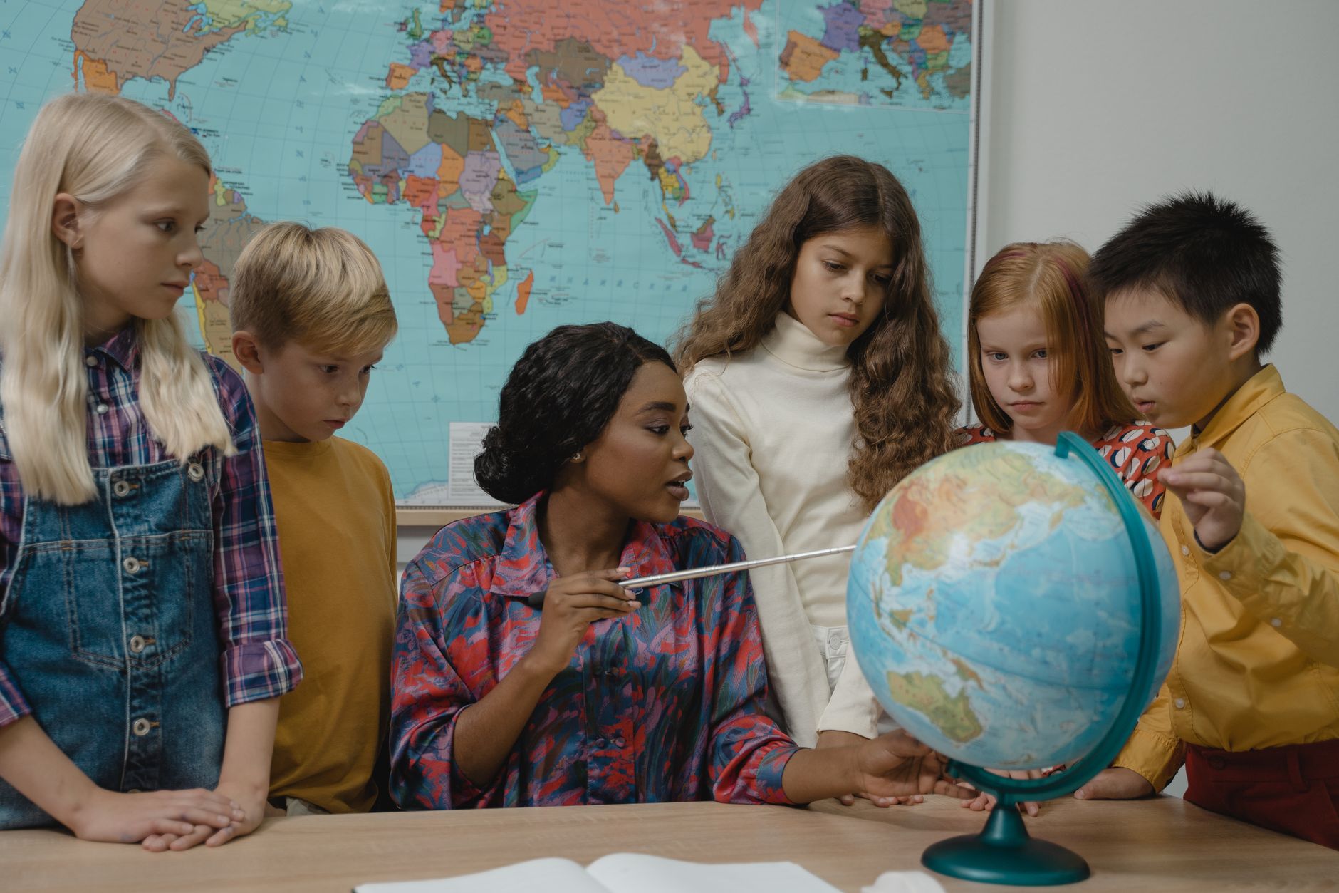 Developing Evidence-Based Global Teaching Practice — Diverse elementary students learning geography with a teacher and globe in the classroom.