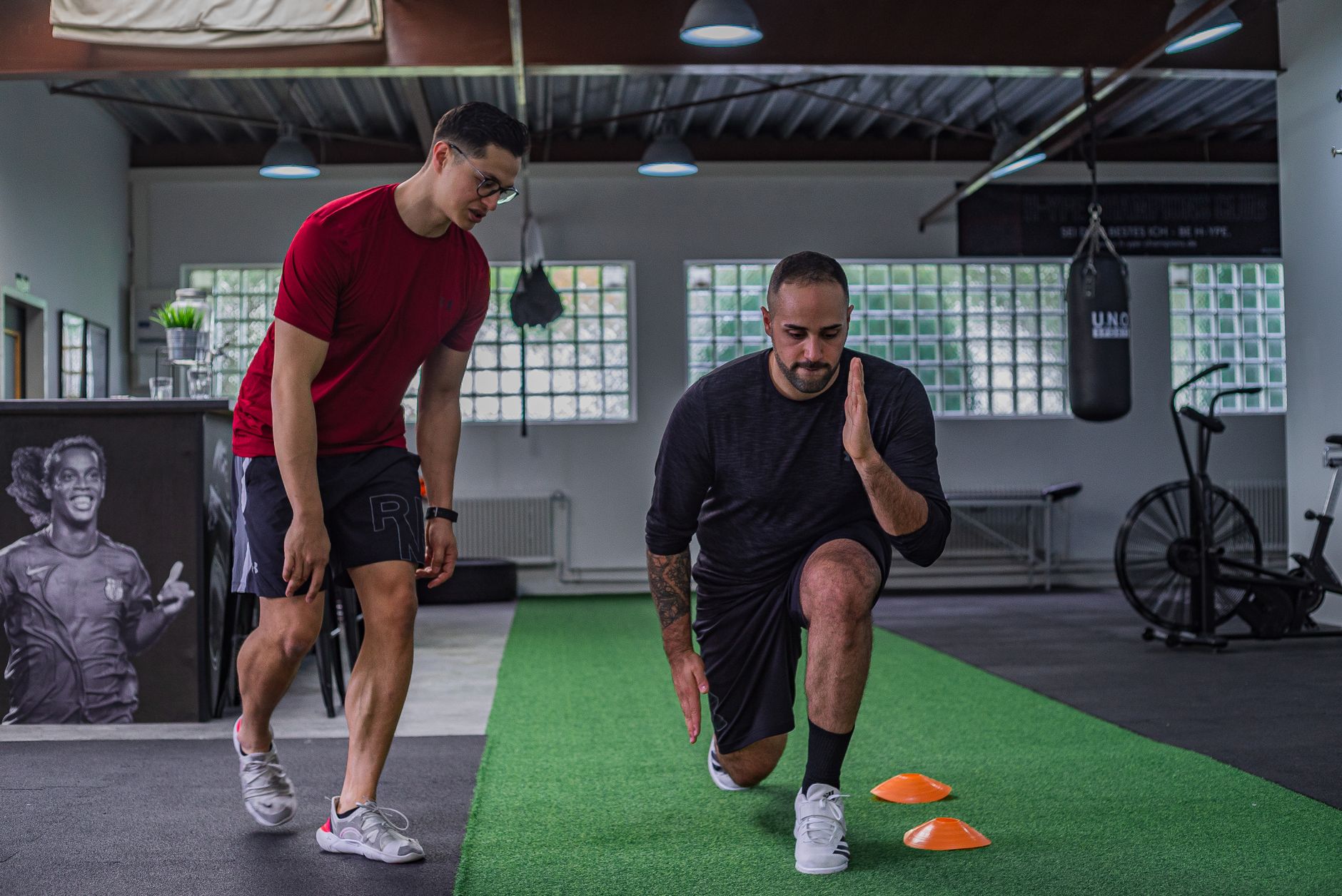 Action Planning and Goal Setting for Coaching — Full body of focused man in sportswear doing stretching exercises with coach in contemporary fitness center