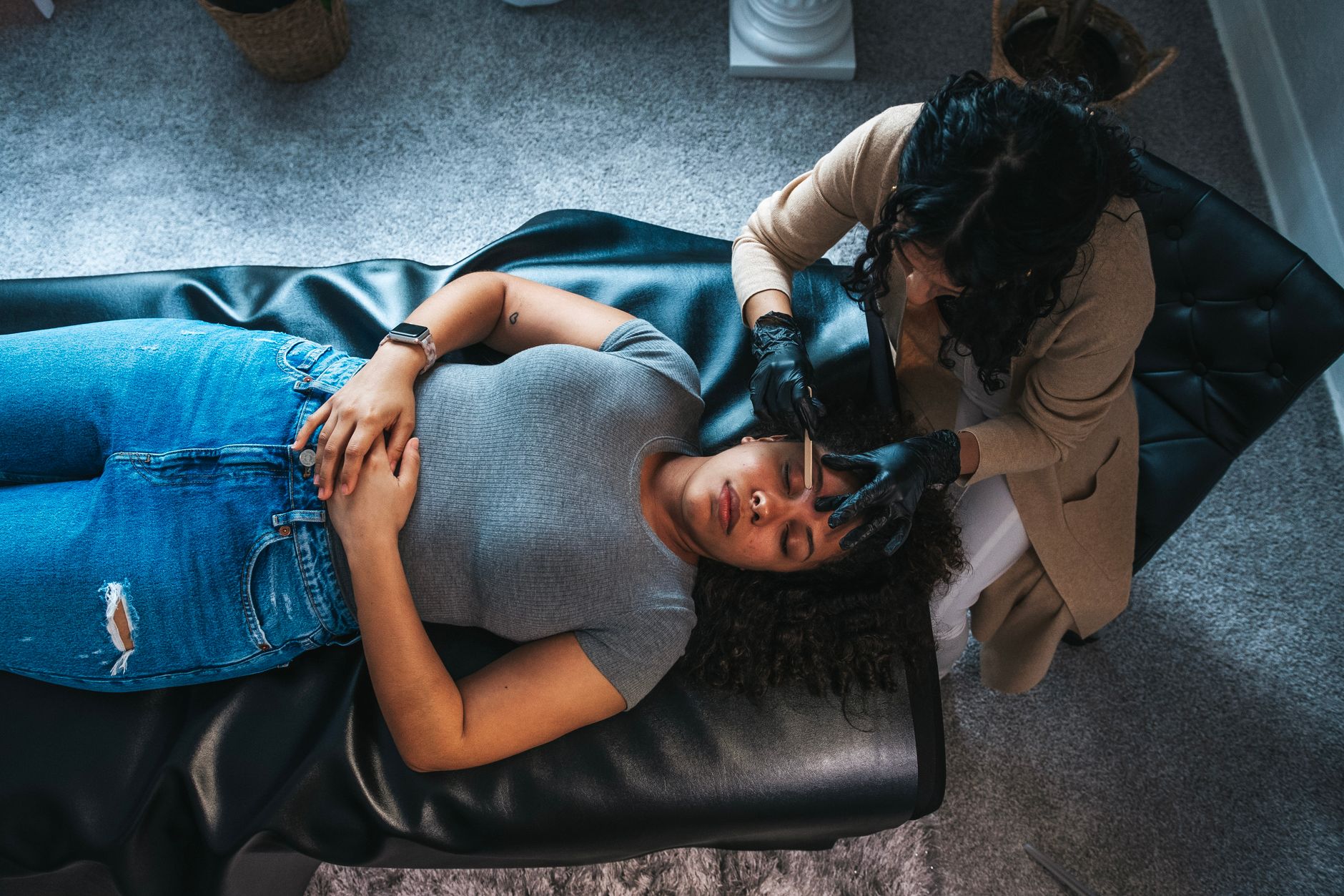 Client consultation for aesthetic procedures — A woman receiving a skincare facial treatment from an esthetician in a modern spa environment.
