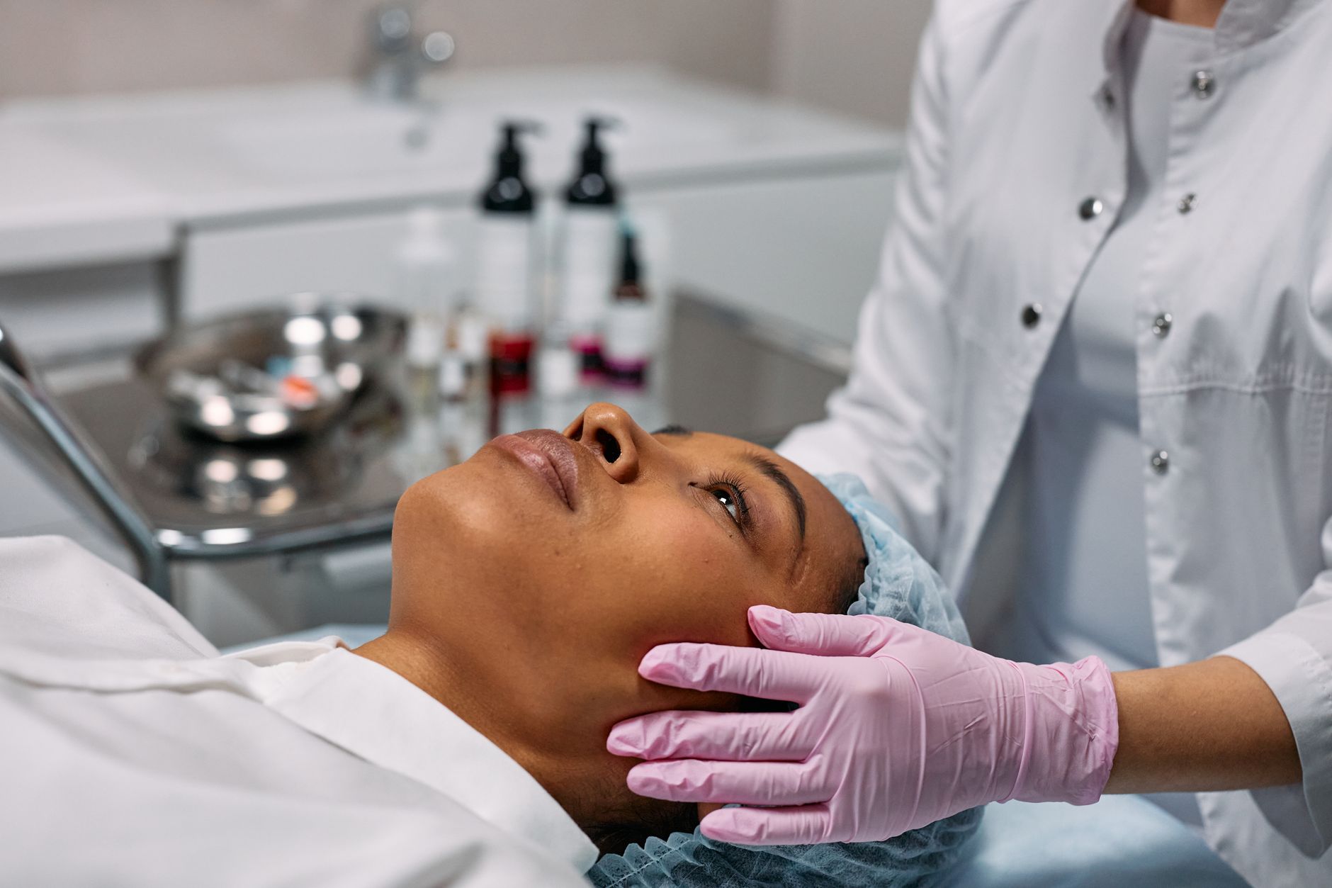 Client consultation for aesthetic procedures — An expert administering a facial treatment to a woman in a modern skincare clinic.