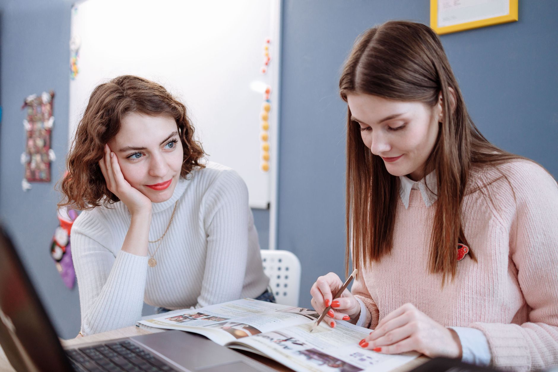 Micropigmentation techniques to enhance lips — Two women collaborating in a classroom setting with a laptop and books, focused on learning.