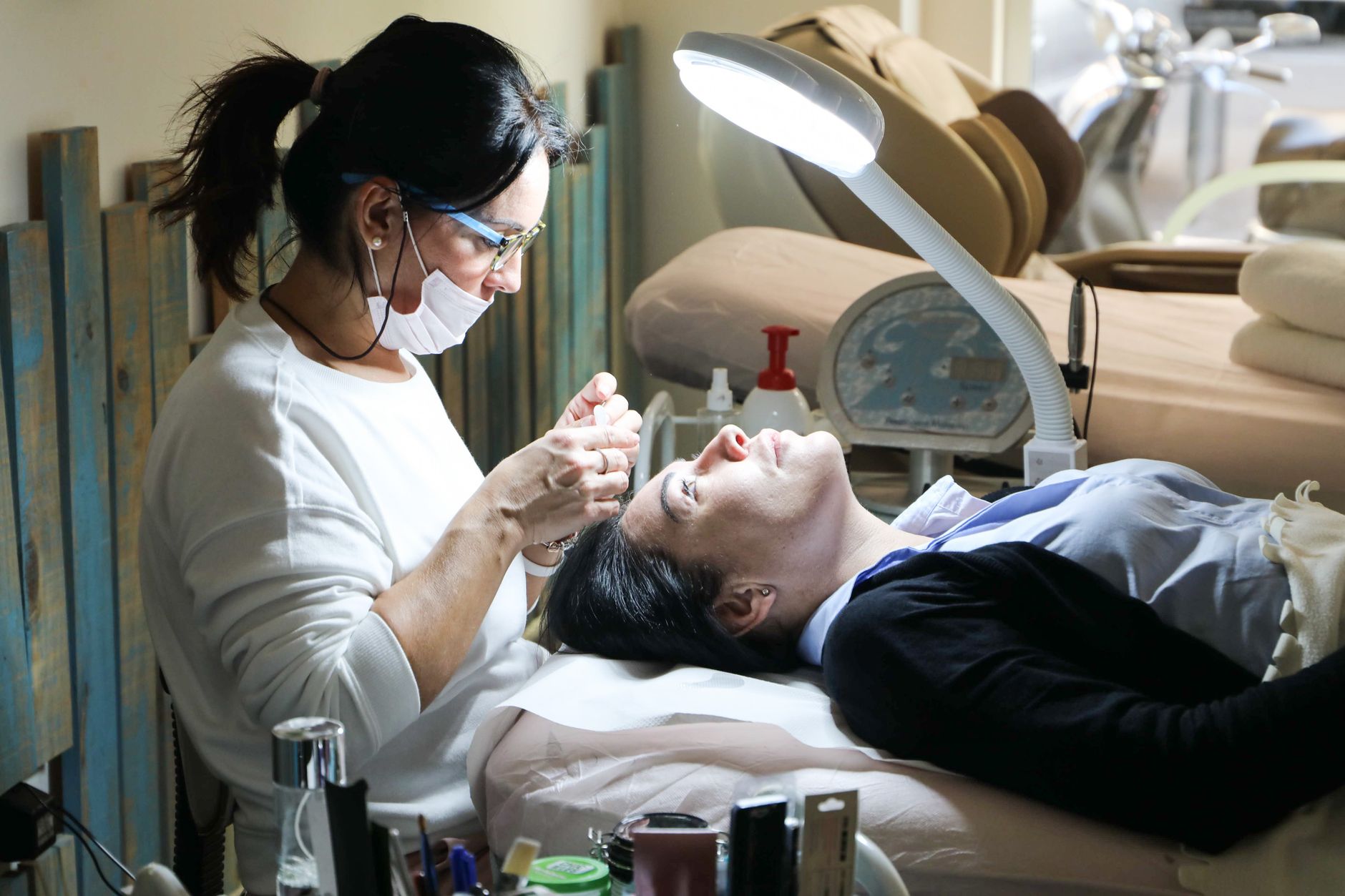 Client consultation for aesthetic procedures — Beautician carefully performs a facial treatment on a woman in a spa setting, ensuring relaxation and care.
