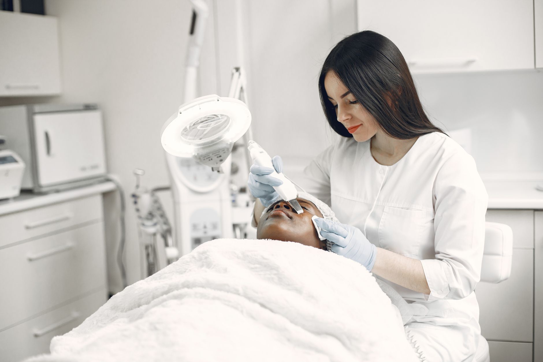 Health, safety and hygiene for aesthetic procedures — A skilled practitioner performs a relaxing facial treatment, promoting wellness and skincare in a modern clinic.