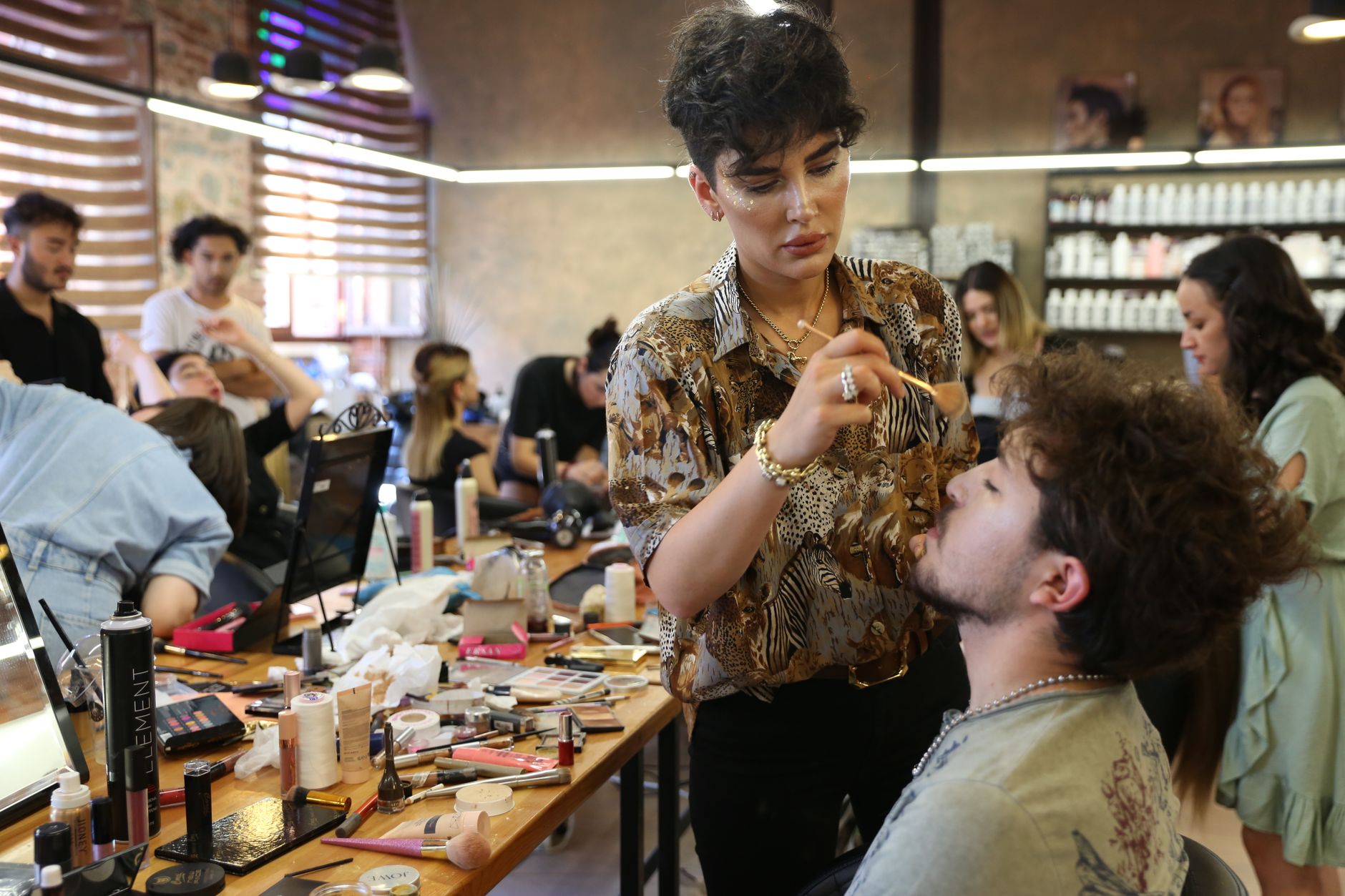 Client consultation for aesthetic procedures — A team of makeup artists working on models in a bustling studio environment.