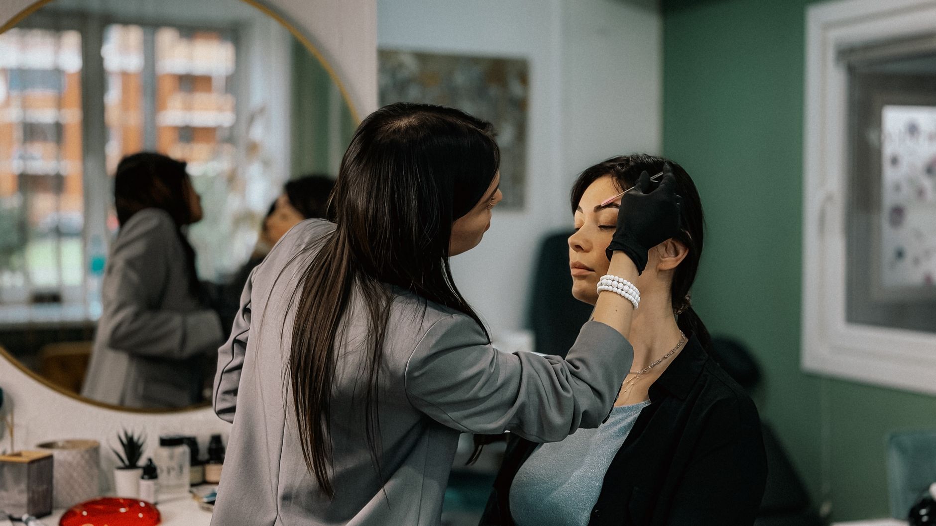 Client consultation for aesthetic procedures — A makeup artist professionally applies eyebrow makeup to a female client in a salon.