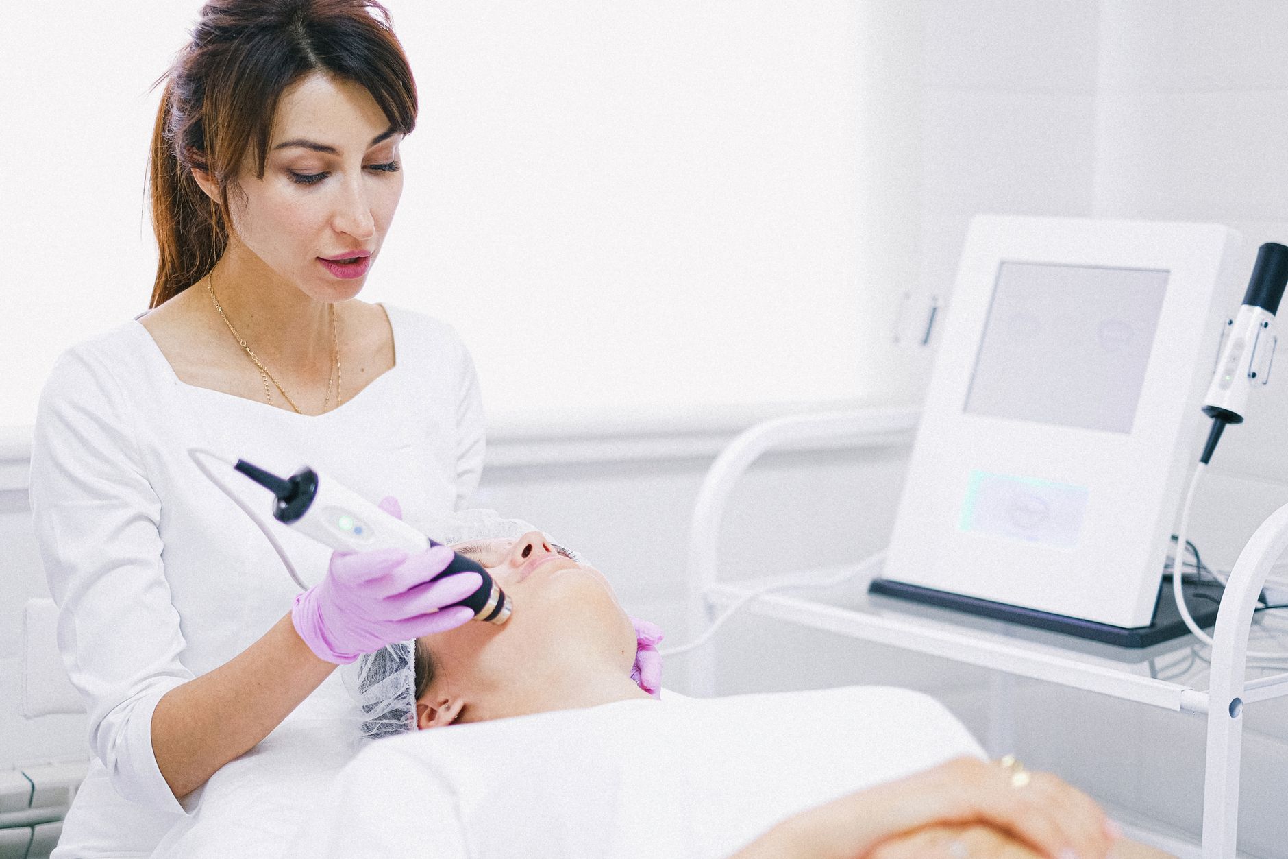 Skin rejuvenation using laser, light and energy-based devices — Aesthetician providing a laser facial treatment to a patient in a spa clinic setting.