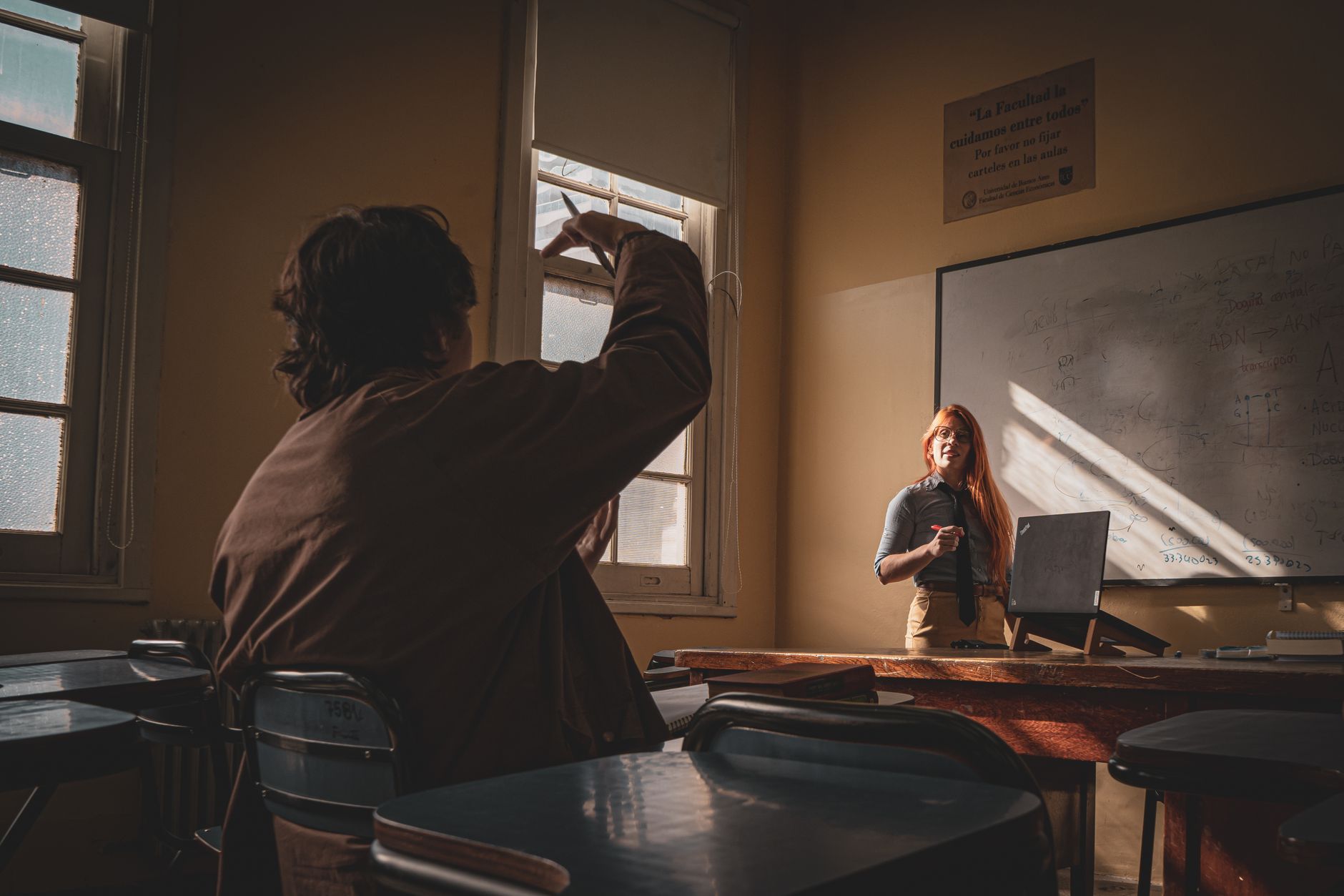 units, and a minimum of three units from the — A teacher interacts with a student in a sunlit classroom setting, fostering learning and engagement.