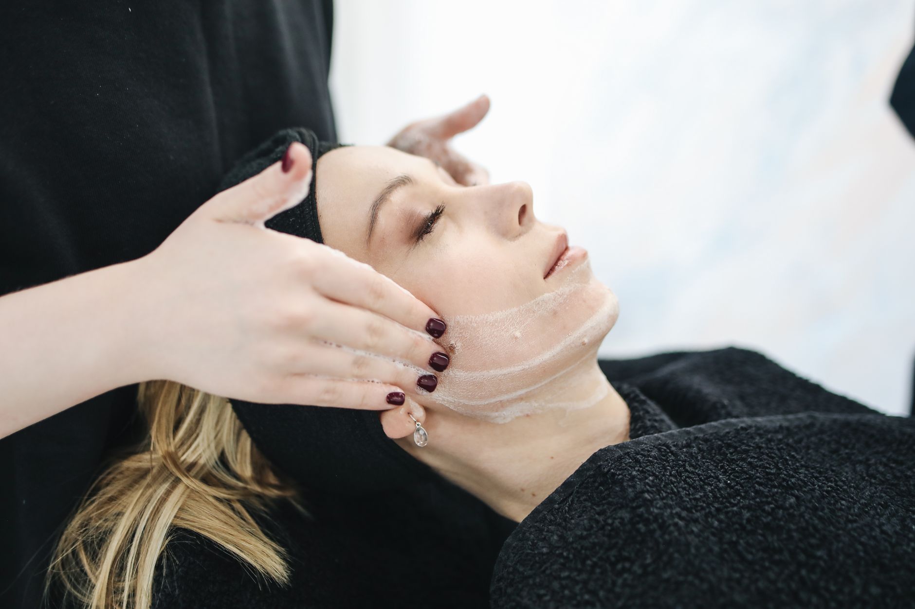 Skin morphology and the inflammatory response — Side view of a woman receiving a soothing facial treatment at a spa, promoting wellness and skincare.
