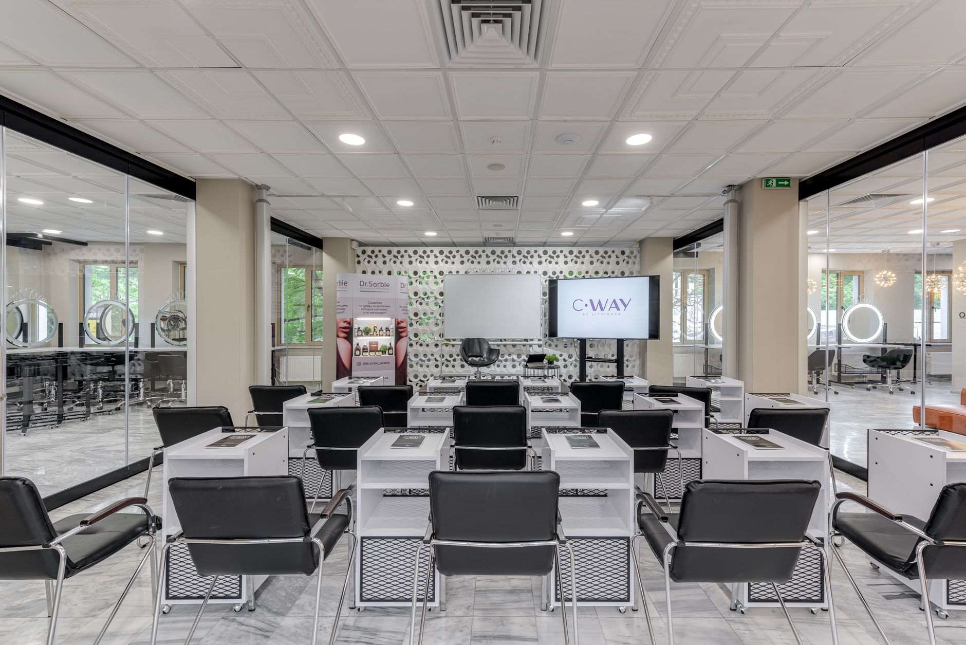 Skin rejuvenation using dermaplaning — Bright and modern hair salon training area featuring rows of black chairs and equipped desks.