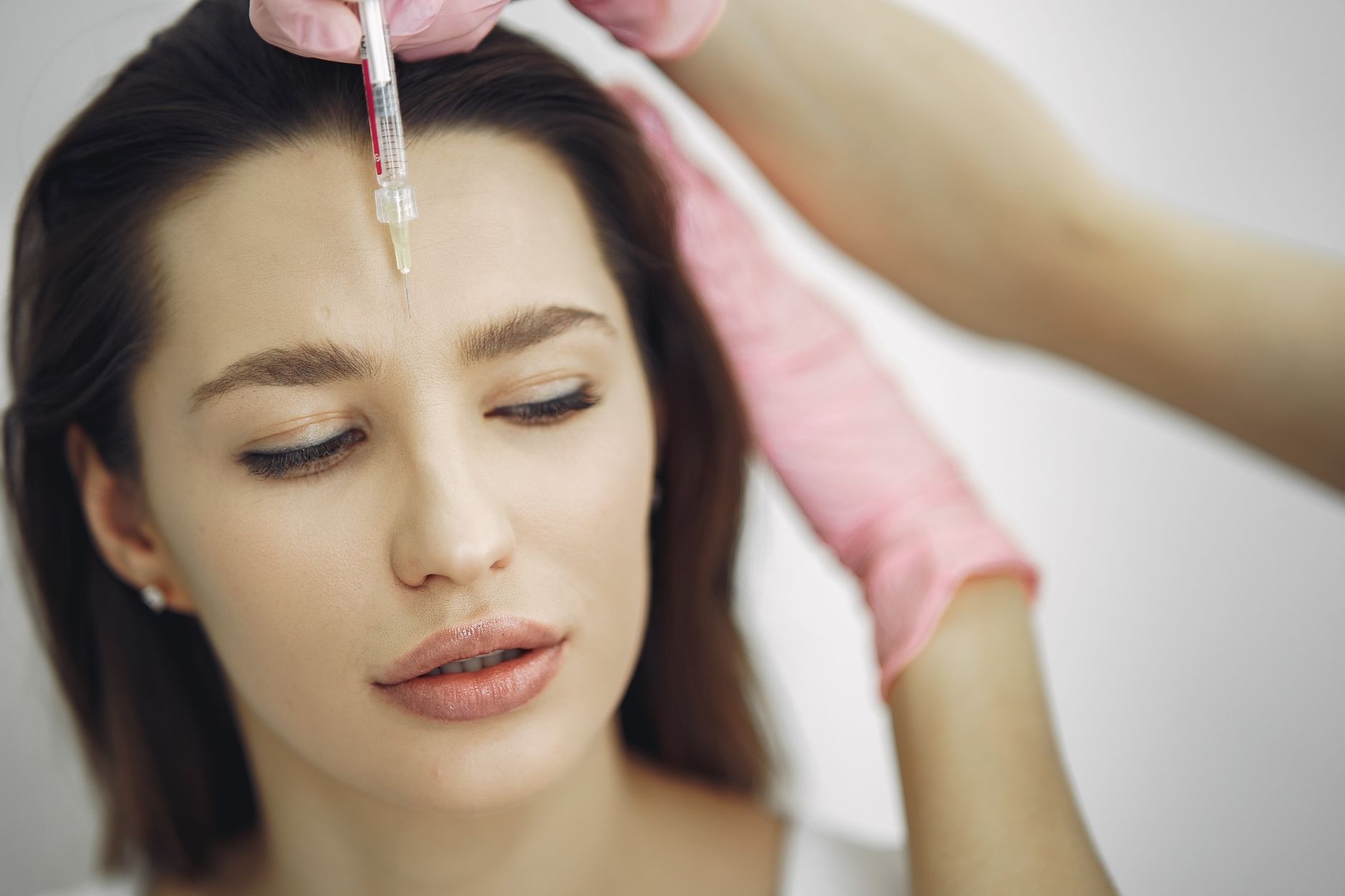 Skincare to support aesthetic procedures — Close-up of facial treatment with injection in a spa setting, focusing on the forehead.