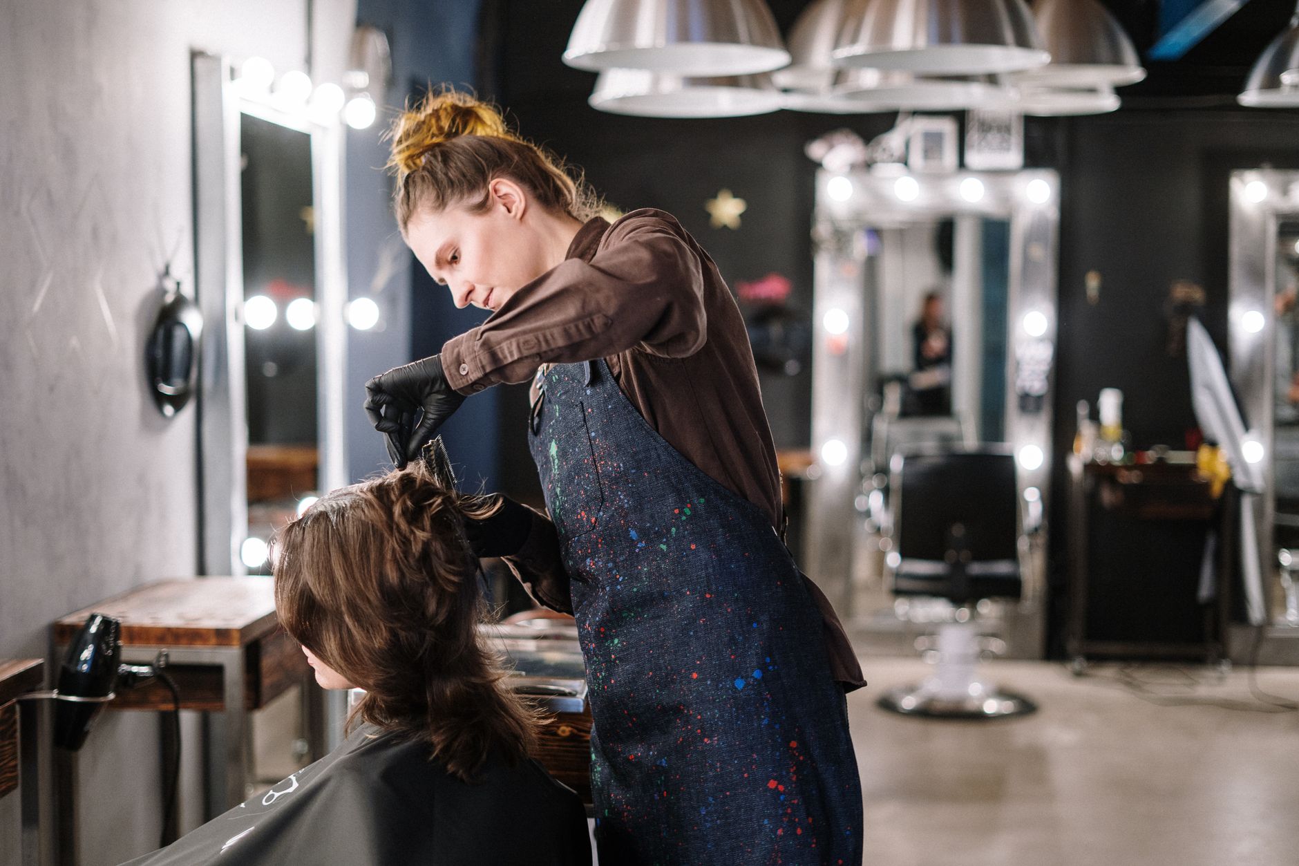 units – 29 credits — A female stylist expertly applying hair color to a client in a modern salon setting.