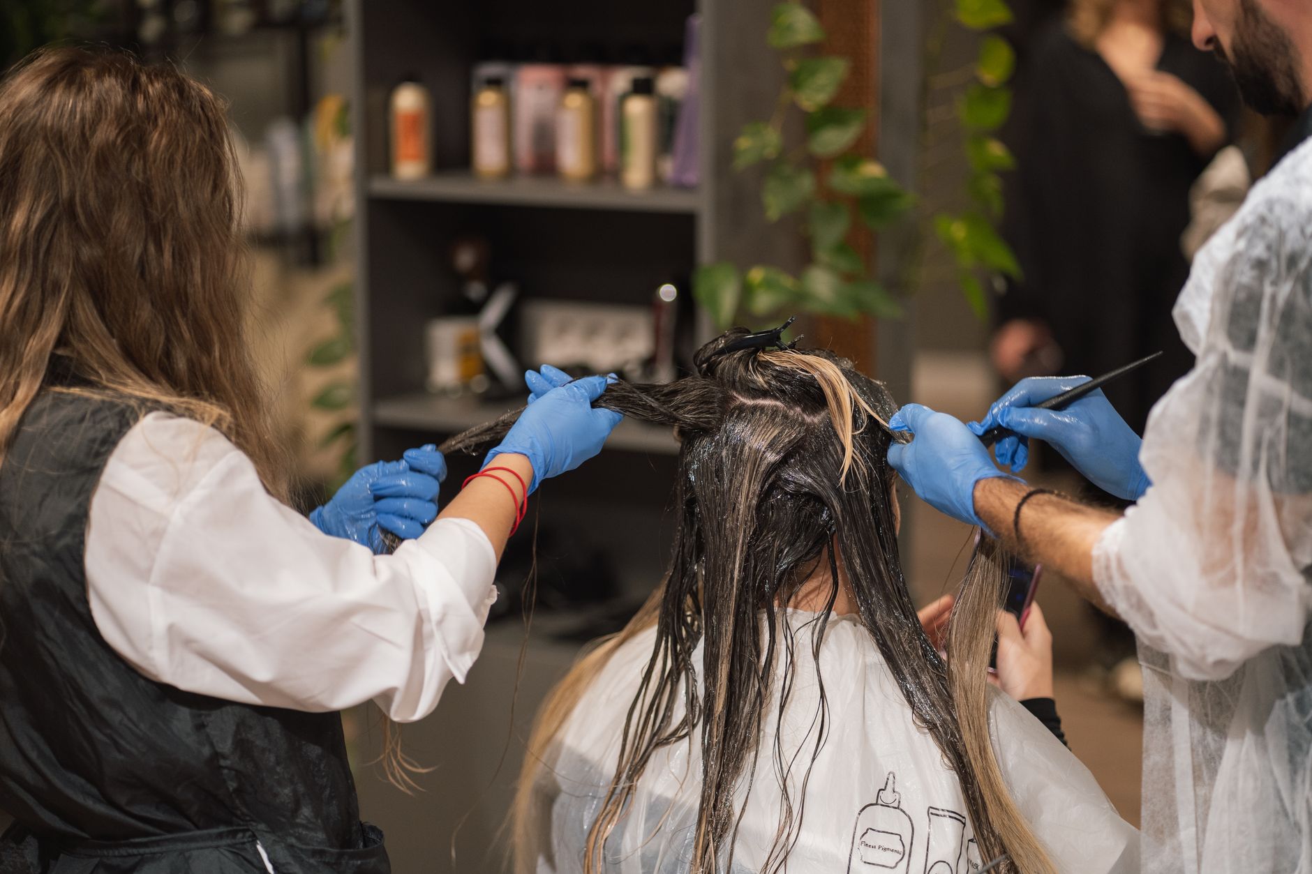 Legal, Regulatory, and Clinical Requirements for Aesthetic Practice — Professional stylists dyeing a woman's hair in a modern salon setting, showcasing teamwork and expertise.