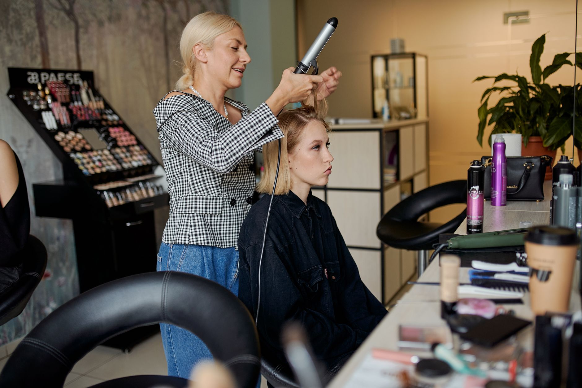Needlestick Injury, Infection Prevention and Control — Side view of adult hairstylist straightening hair of client with iron in hairdressing salon