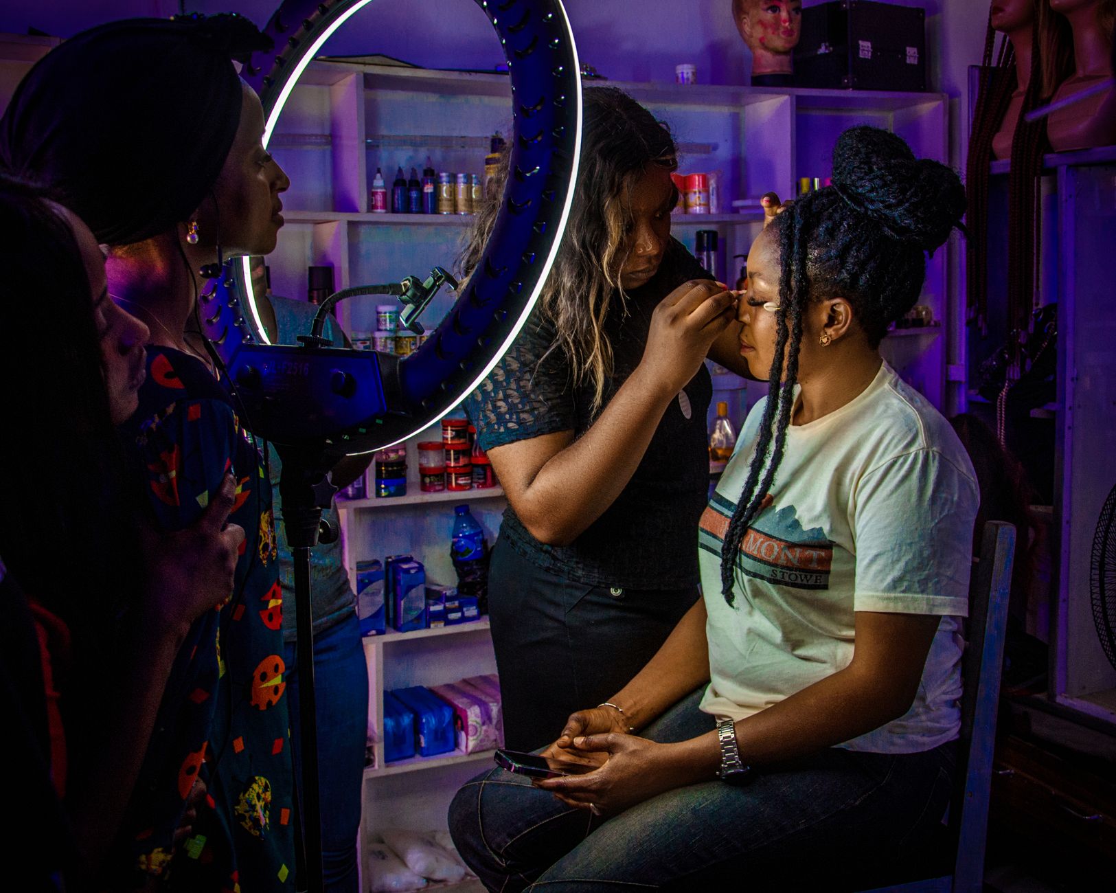 unitsand a minimum of 1 — Makeup artist applying cosmetics to a client under studio lighting in jos, nigeria.