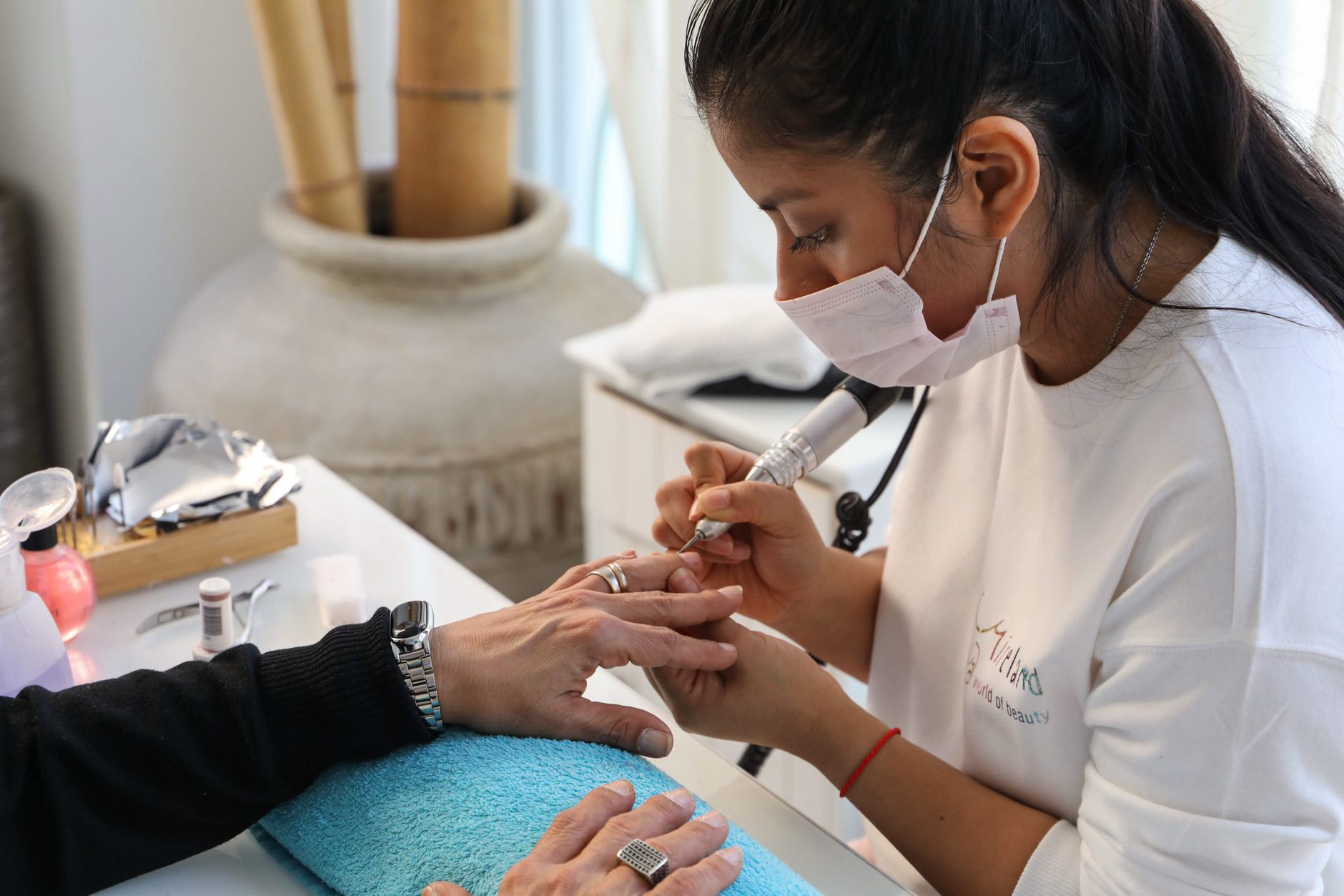 Complication Management for Aesthetic Practice — Nail technician performing a manicure with precision and care in a salon setting.