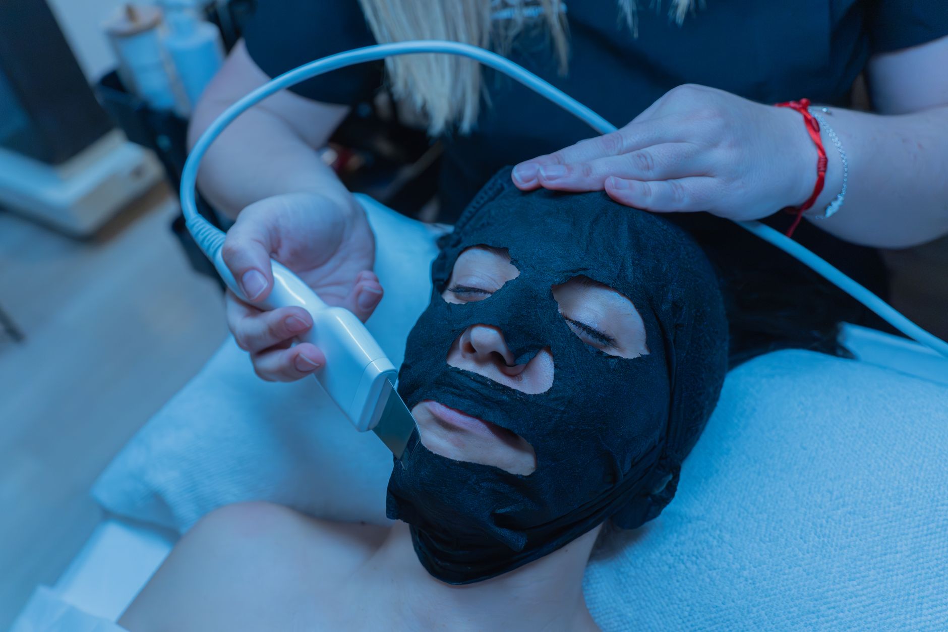 Advanced Aesthetic Procedures: Radio Frequency — Person receiving a facial treatment with a black charcoal mask in a spa setting.