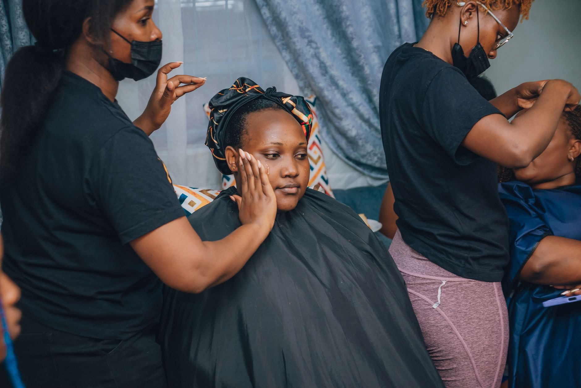 Client consultation — A bride receives makeup and styling assistance before her wedding in an indoor setting.