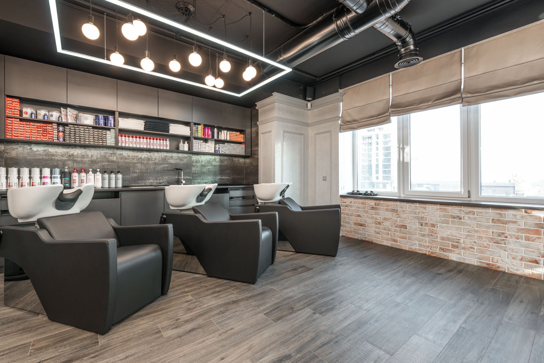 Advise on products and services — Modern leather chairs with backwash sinks placed in modern spacious beauty salon with windows and various professional supplies under glowing lamps