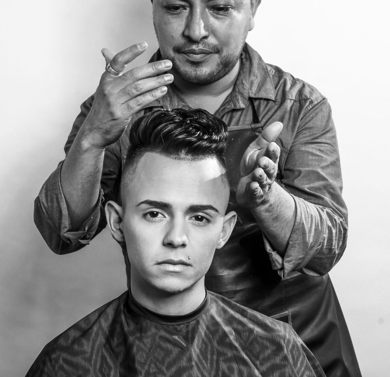 Traditional barber haircuts — A hairstylist carefully styles a young man's hair in a professional salon setting, emphasizing modern grooming techniques.
