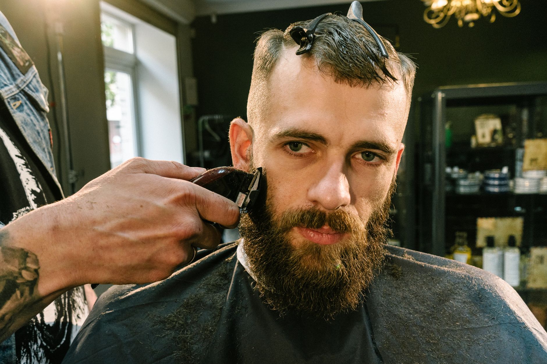 Shavingg services — Close-up of a barber trimming a bearded man's facial hair in a stylish barber shop.