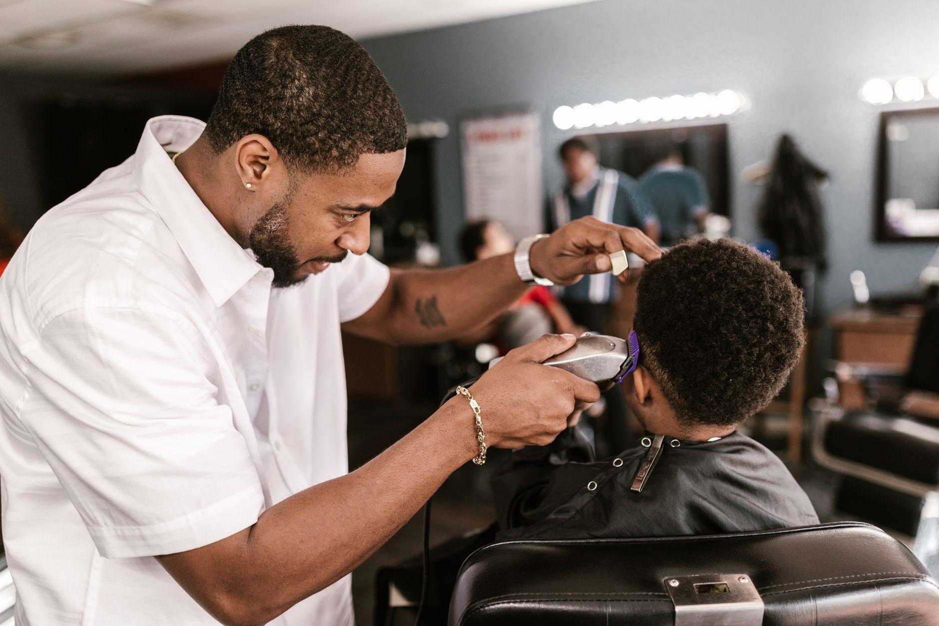 Barbershop business support — Professional barber giving a precise haircut to a client in a stylish barbershop setting.