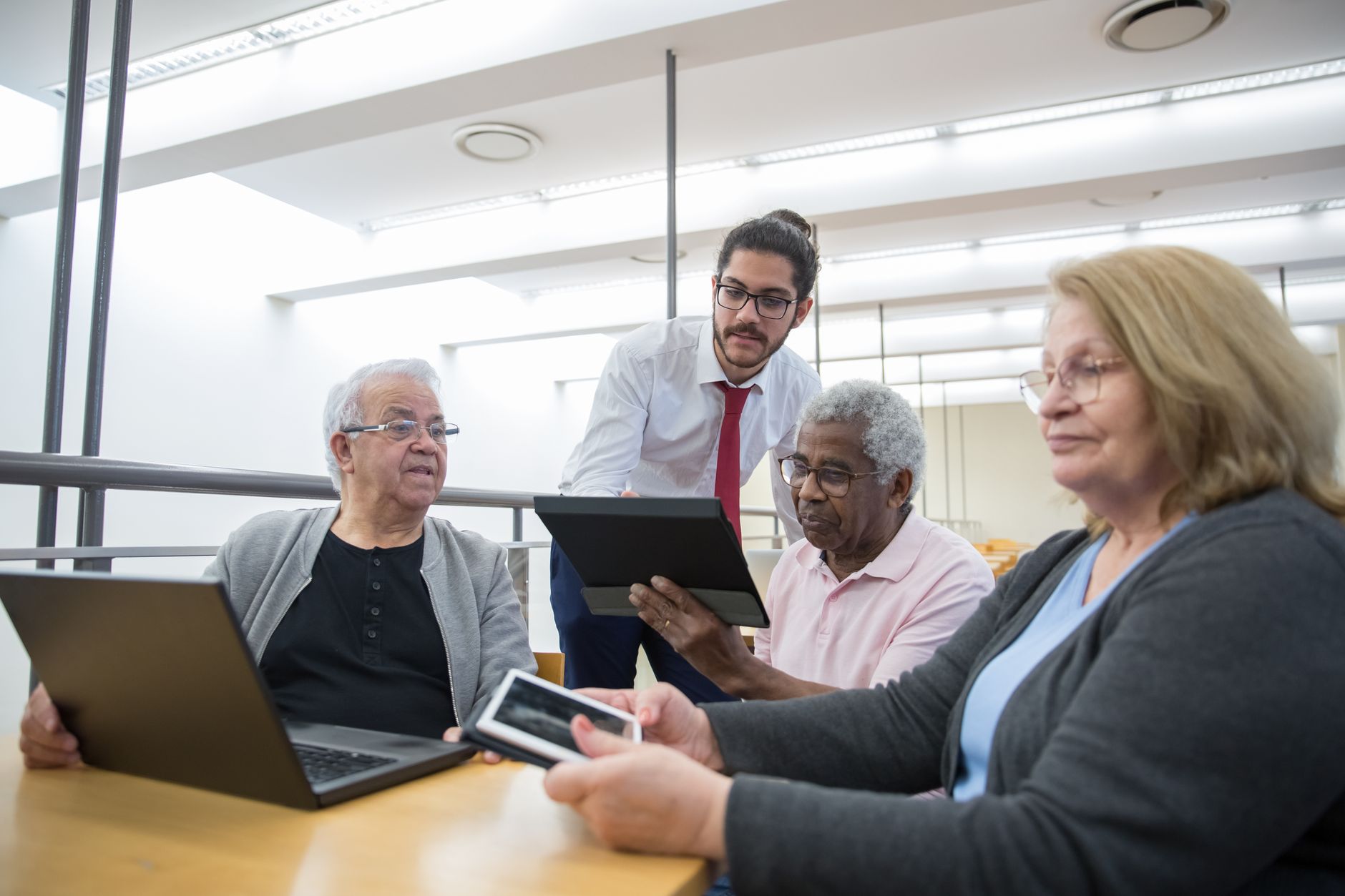 Human Nutrition — Elderly individuals engage in a digital learning workshop, embracing modern technology in a library setting.