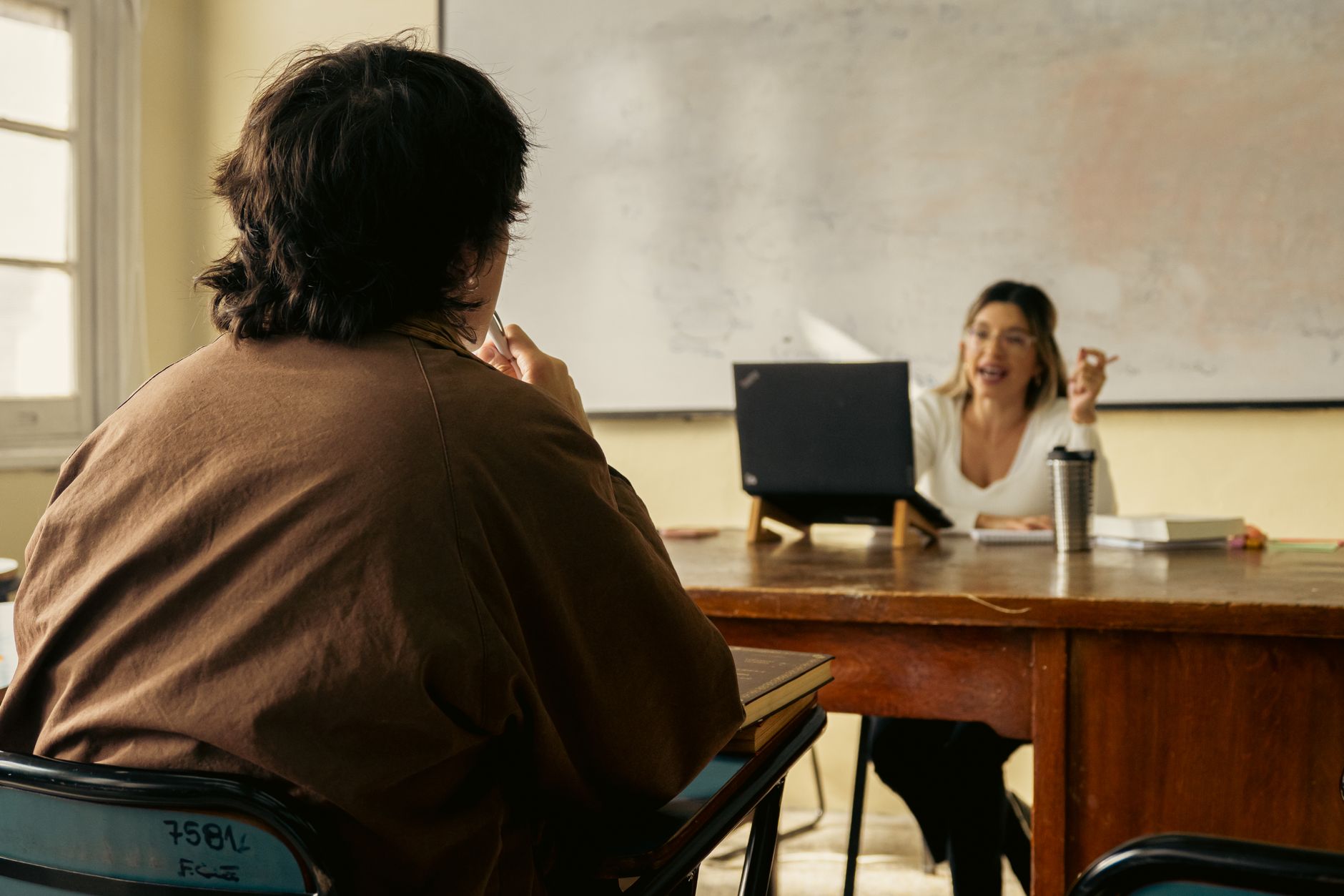Non-Diet Approach to Coaching — Student and teacher engage in discussion in a classroom setting with a laptop and whiteboard visible.