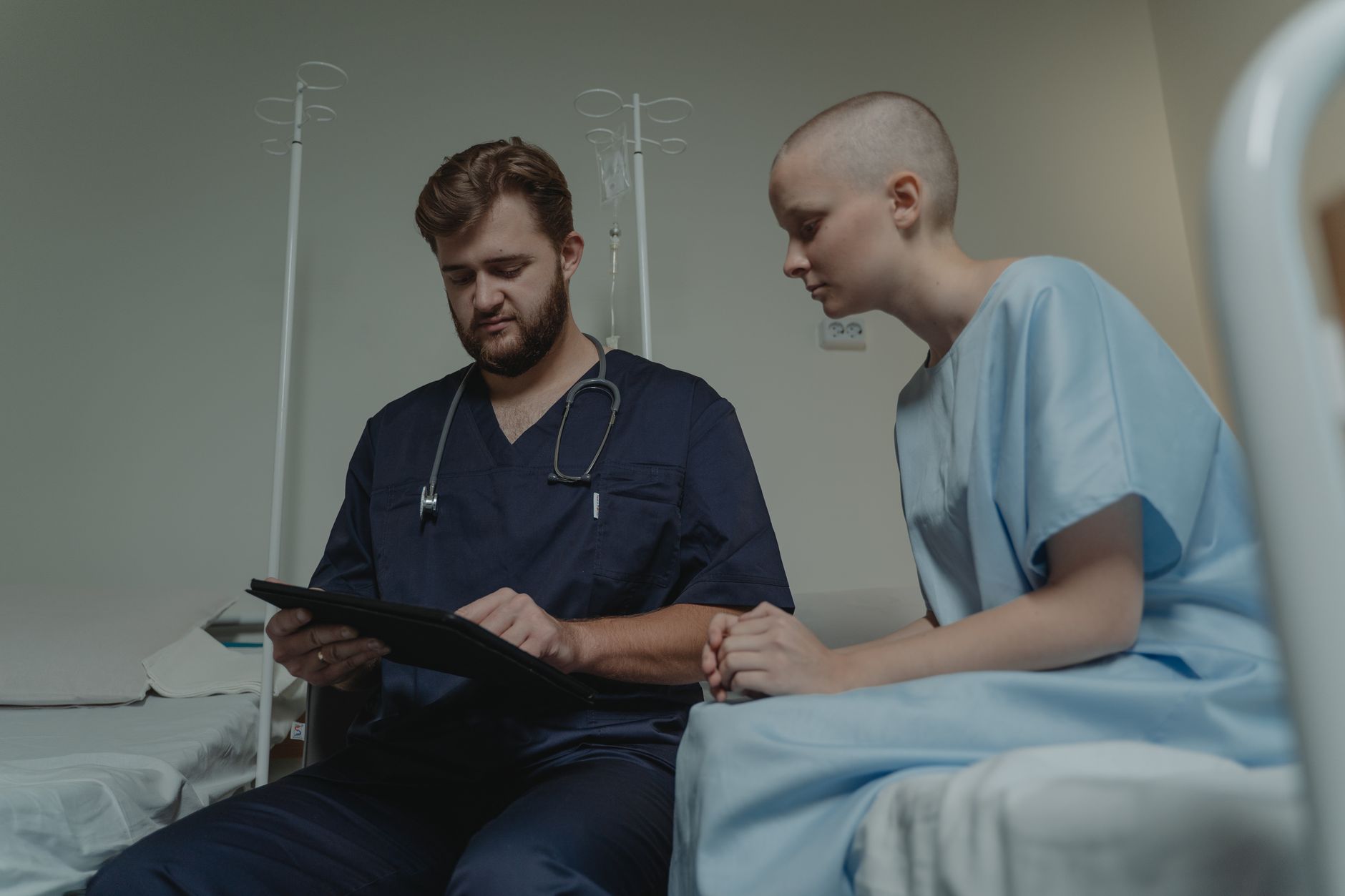 Mental Health and Trauma Awareness — Doctor consulting with a young patient in a hospital room using a digital tablet.