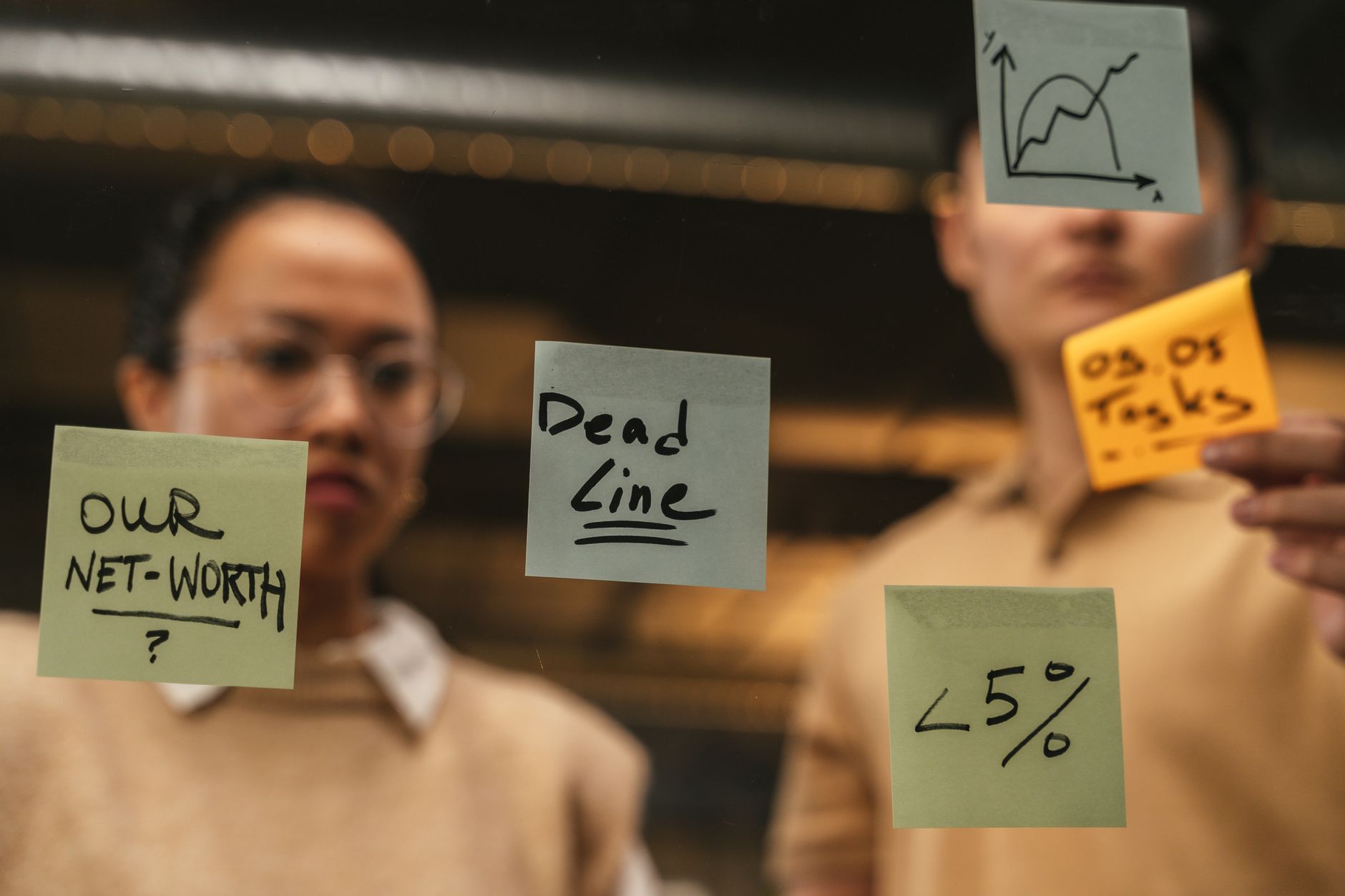 Finance for Strategic Decision-makers — Business professionals collaborating with sticky notes on mirror. teamwork and planning concept.