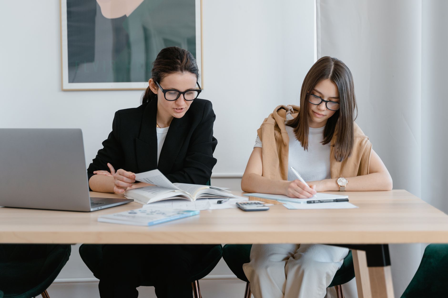 Research Methods and Investigating Psychology — Two women working together with books and a laptop, focused on learning.