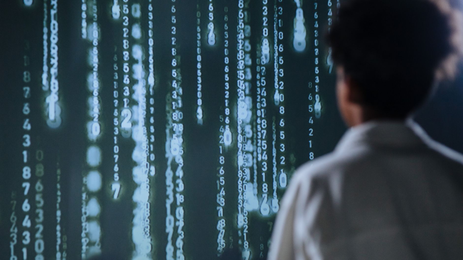 Individual Differences: Intelligence, Personality and Criminology — An individual viewing glowing numbers on a screen, symbolizing technology and data.