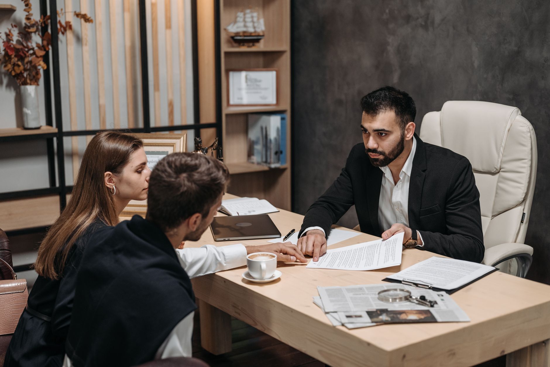 Contract Law — Lawyer discussing legal documents with clients at office desk.