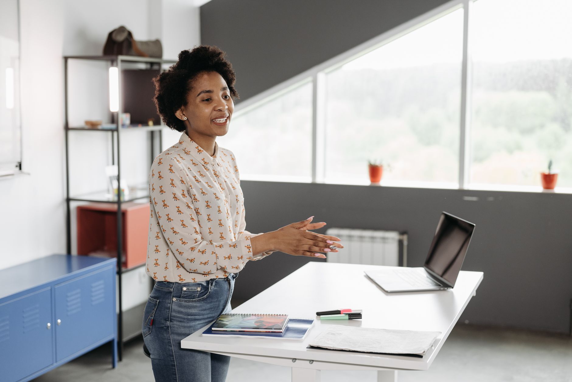 Equity and TrustsEU Law — Young african american woman speaking at a desk with a laptop in a bright office.