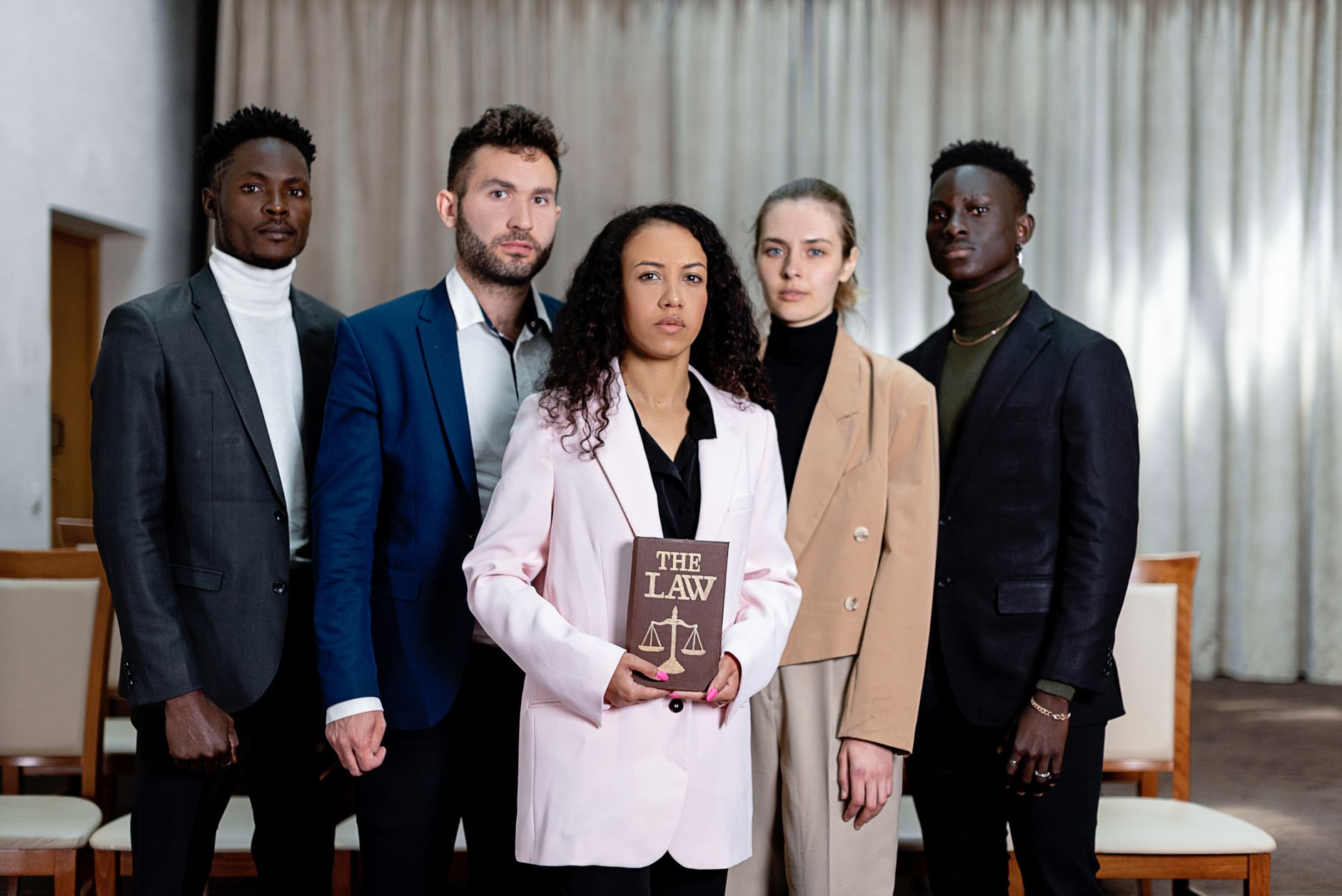 Law of Tort — A diverse group of five lawyers posing confidently with a law book in an office setting.
