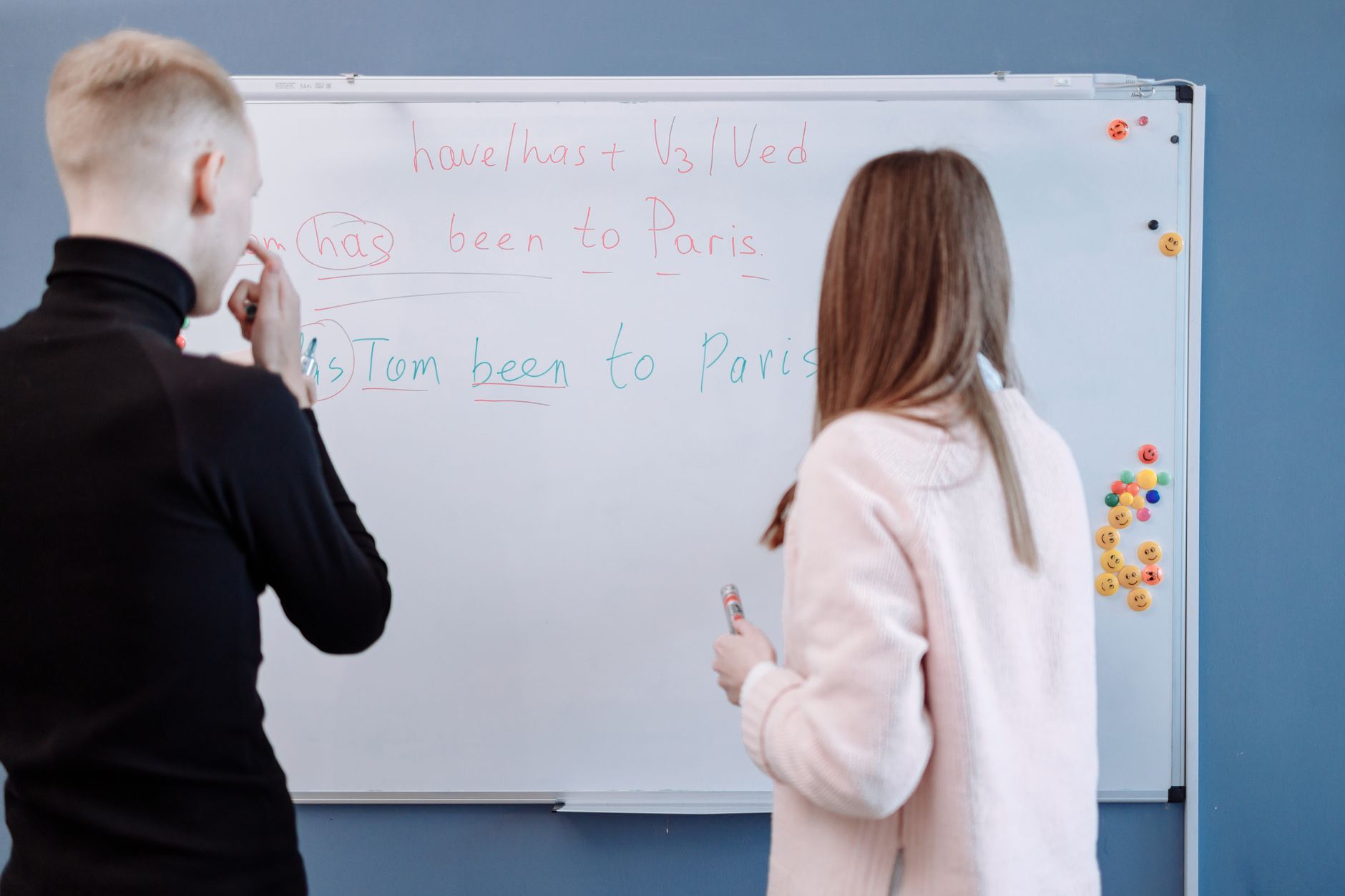 Understanding and teaching English grammar — Two students studying english grammar at a whiteboard in a classroom setting.
