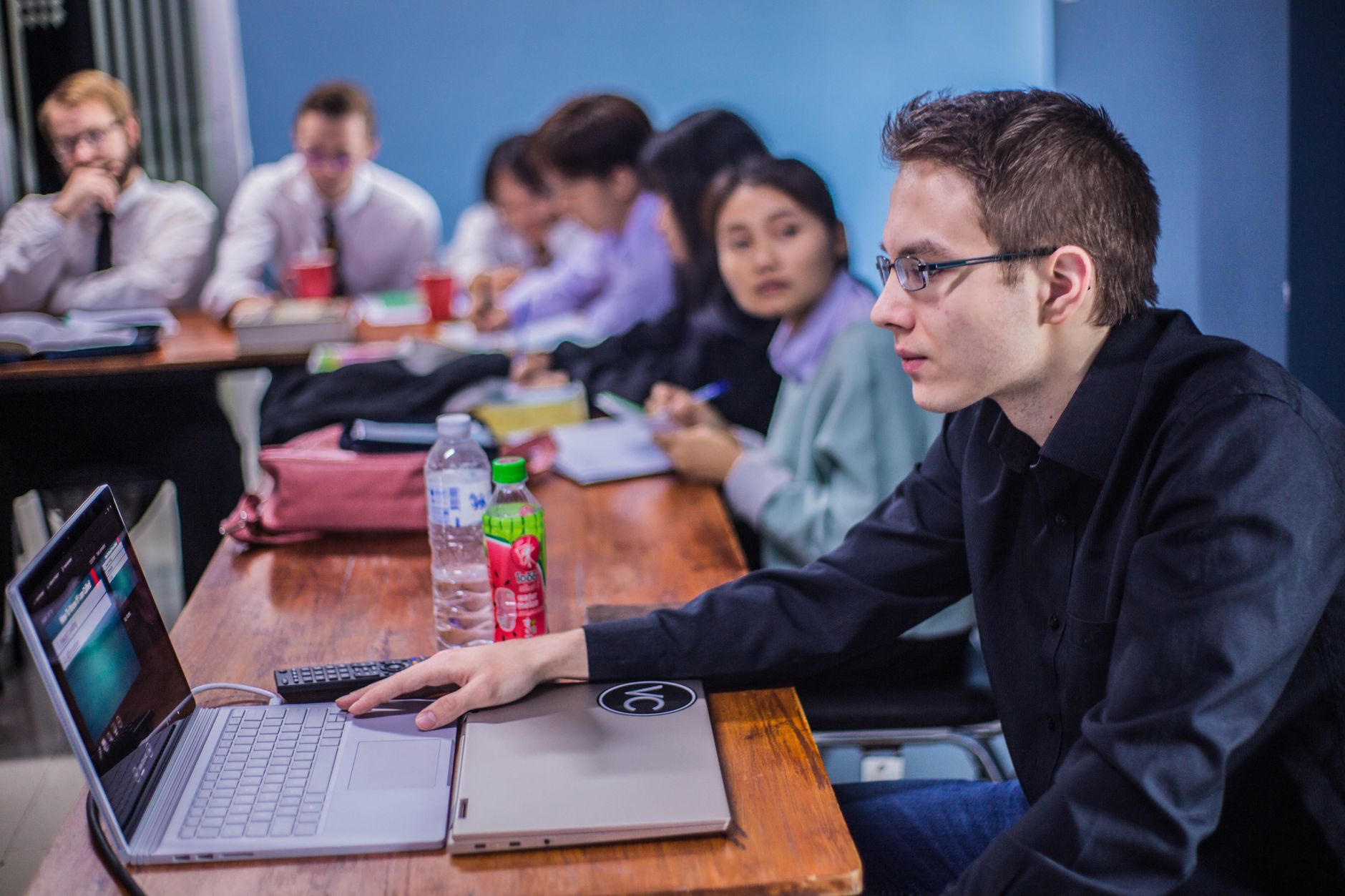 A TEFL toolkit — A group of students working together in a classroom with laptops and documents.