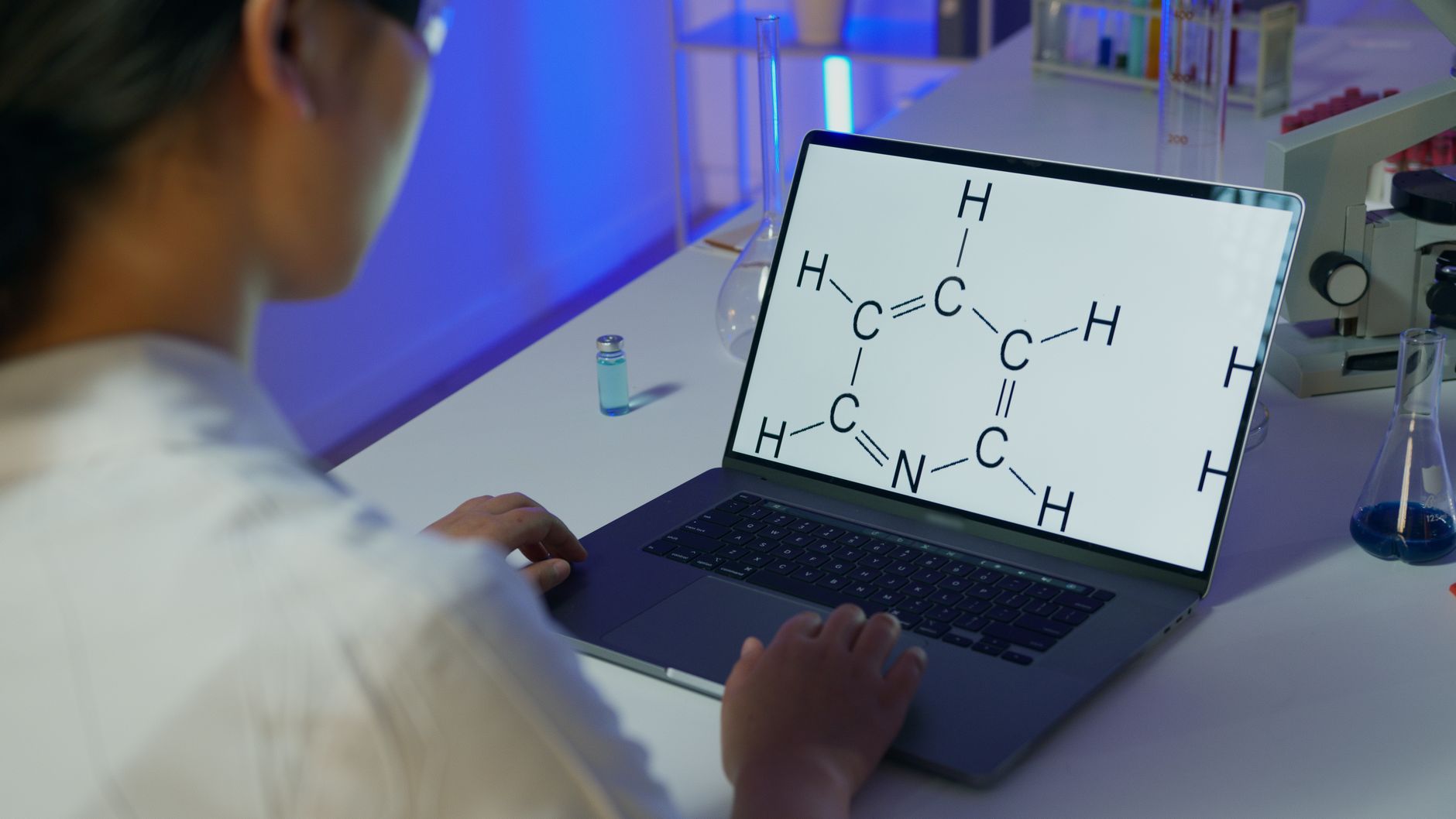 Harnessing Mitochondrial Energy for the Athlete — A scientist reviews a chemical formula on a laptop in a laboratory setting.