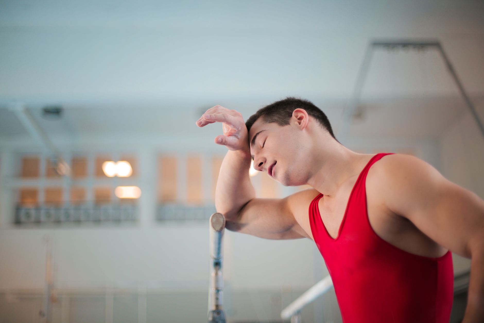 Relative Energy Deficiency in Sport (REDs)A Mind-body Perspective in Sport — Tired gymnast in red leotard resting after intense training session.