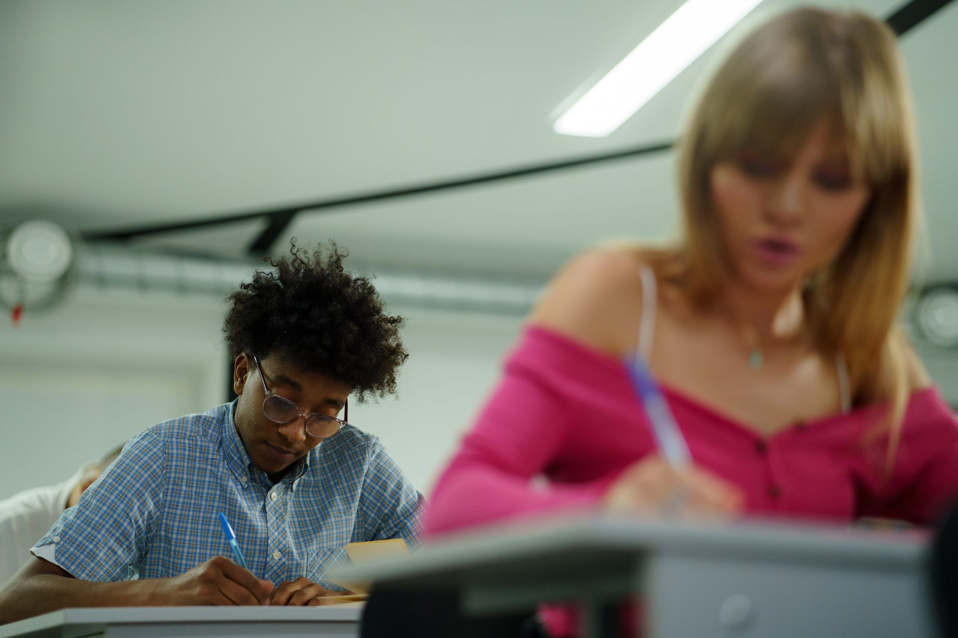 Health, safety and hygiene — Focused high school students writing notes in a classroom setting during a lecture.