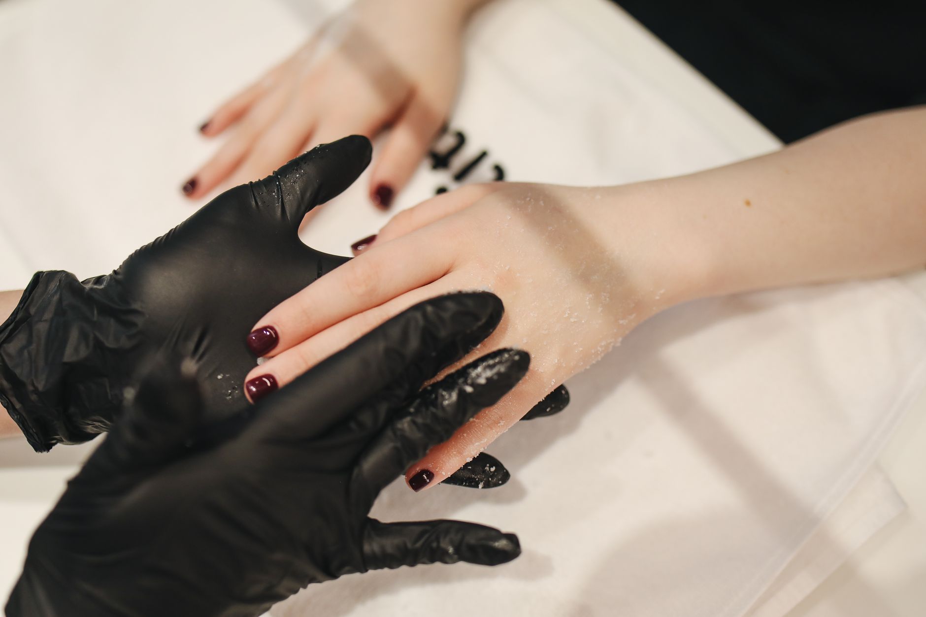 Manicure treatments — Close-up of a relaxing hand treatment session at a spa with black gloves and skincare products.