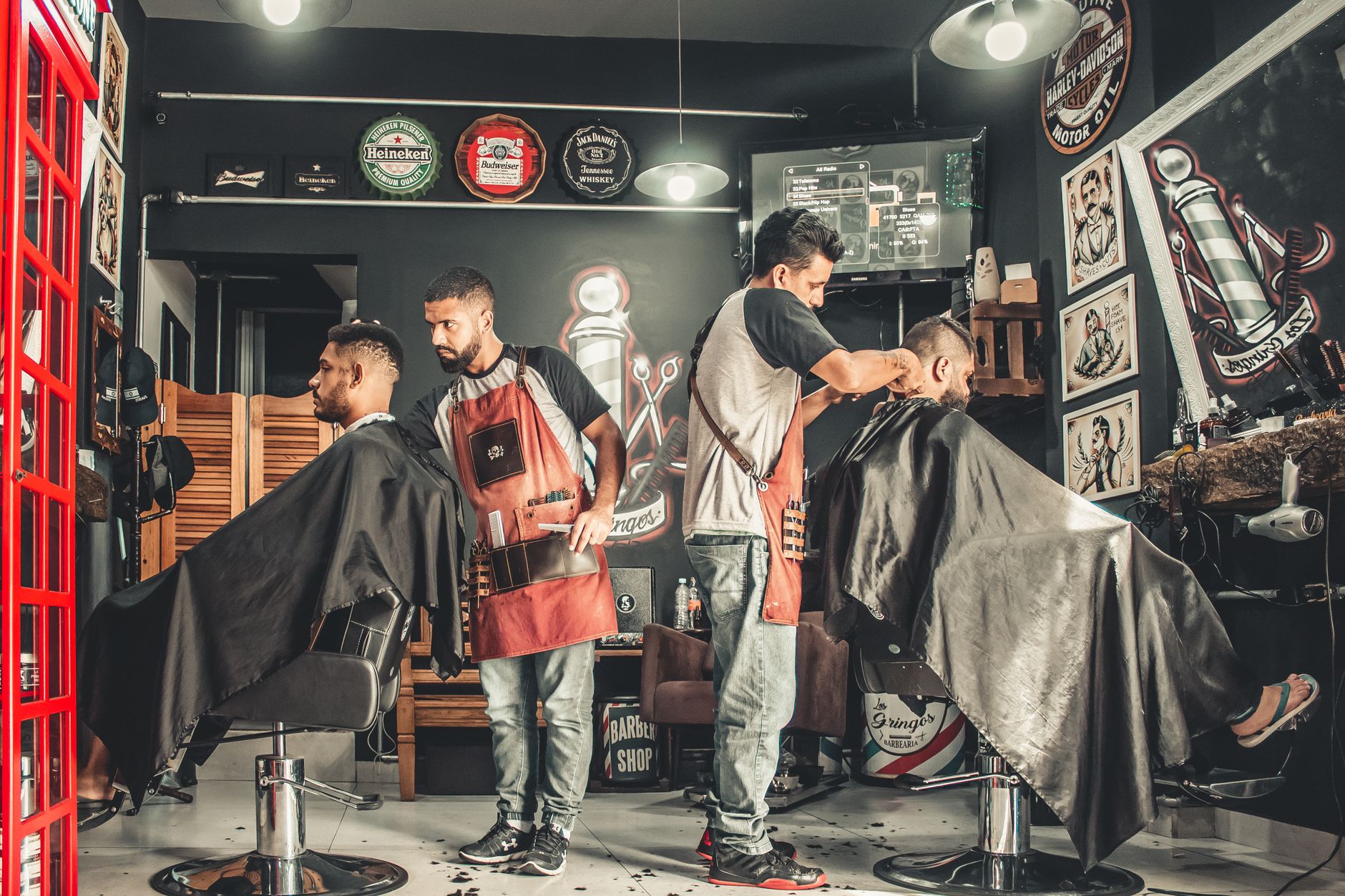 Basic business support — A bustling barbershop with two men getting haircuts, showcasing a vibrant barber environment.