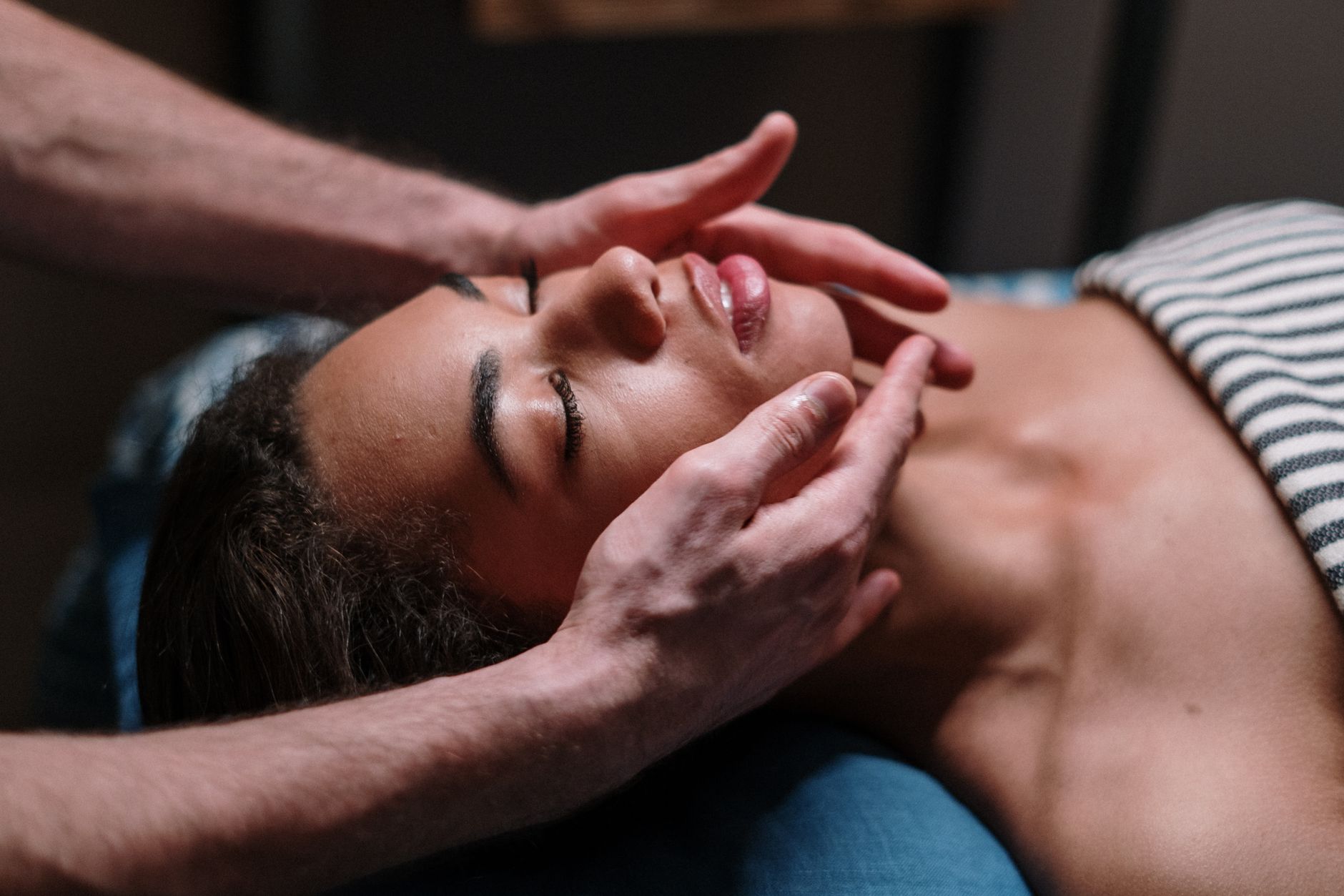 Wellbeing and holistic therapy — Close-up of a woman receiving a soothing facial massage in a serene spa environment.