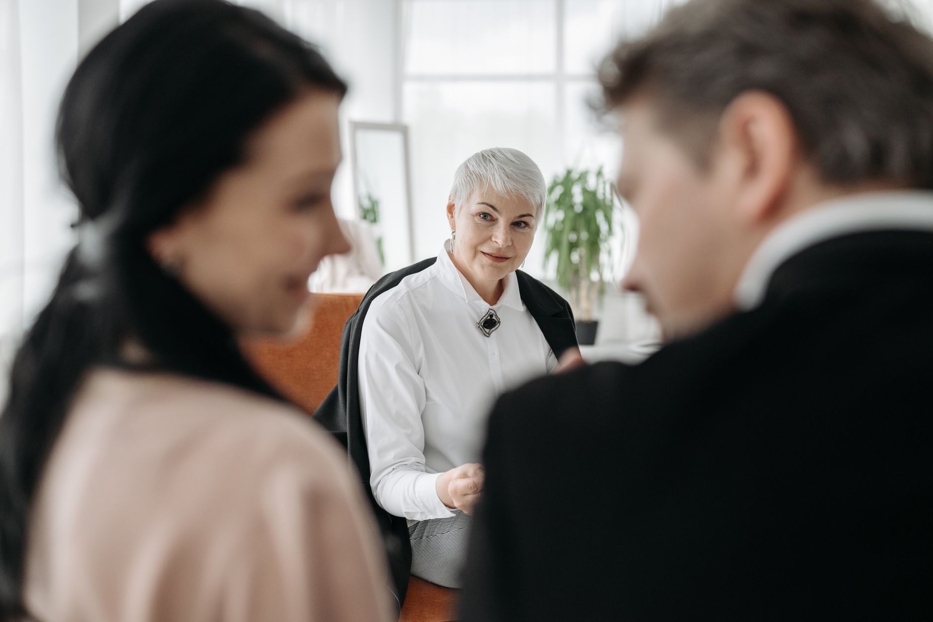 Client consultation and profiling — A professional consultation session with a couple and a social worker in a modern office environment.
