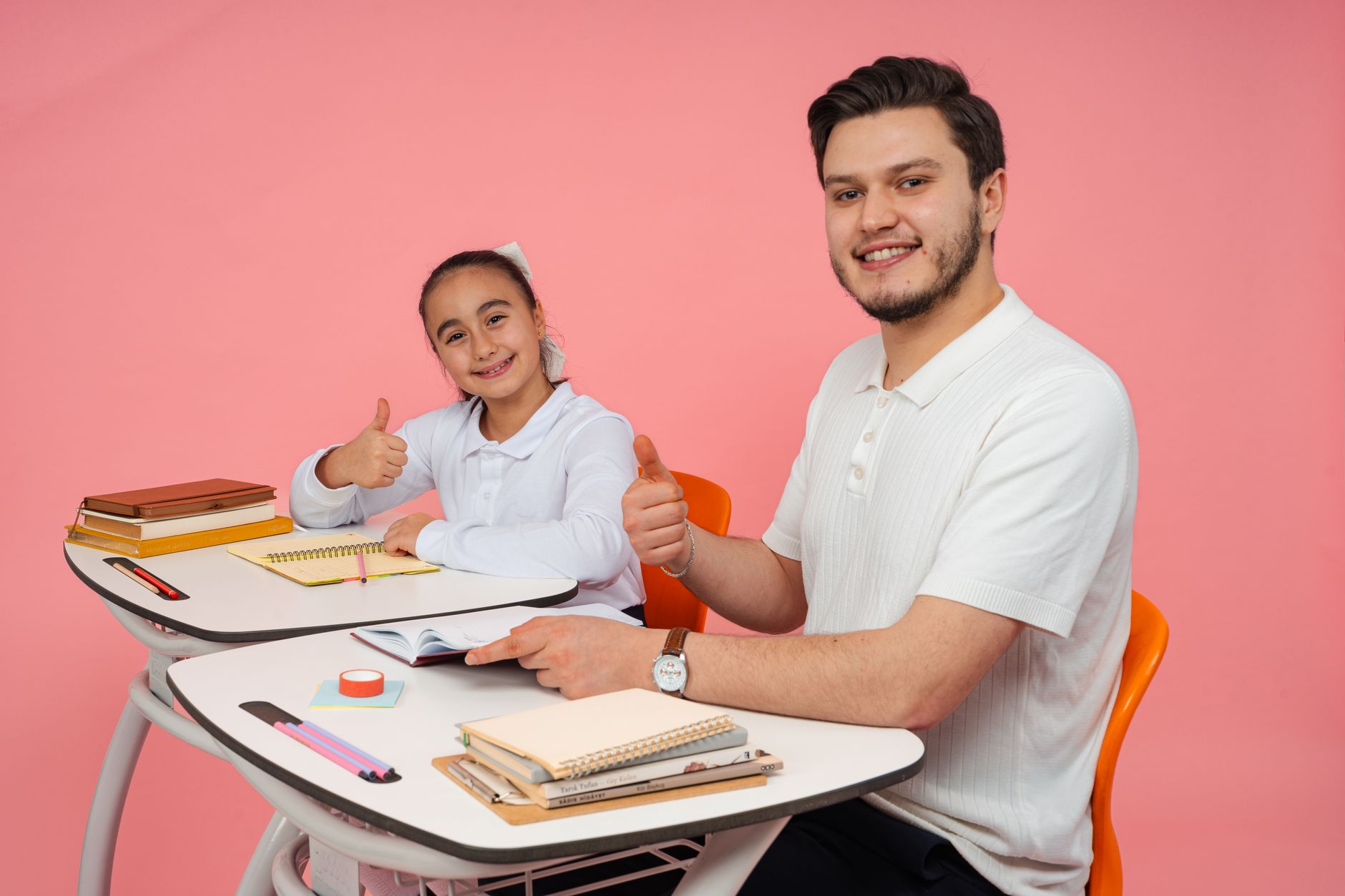 Body electrotherapy — Smiling teacher and student at a desk, thumbs up, promoting education and positivity.